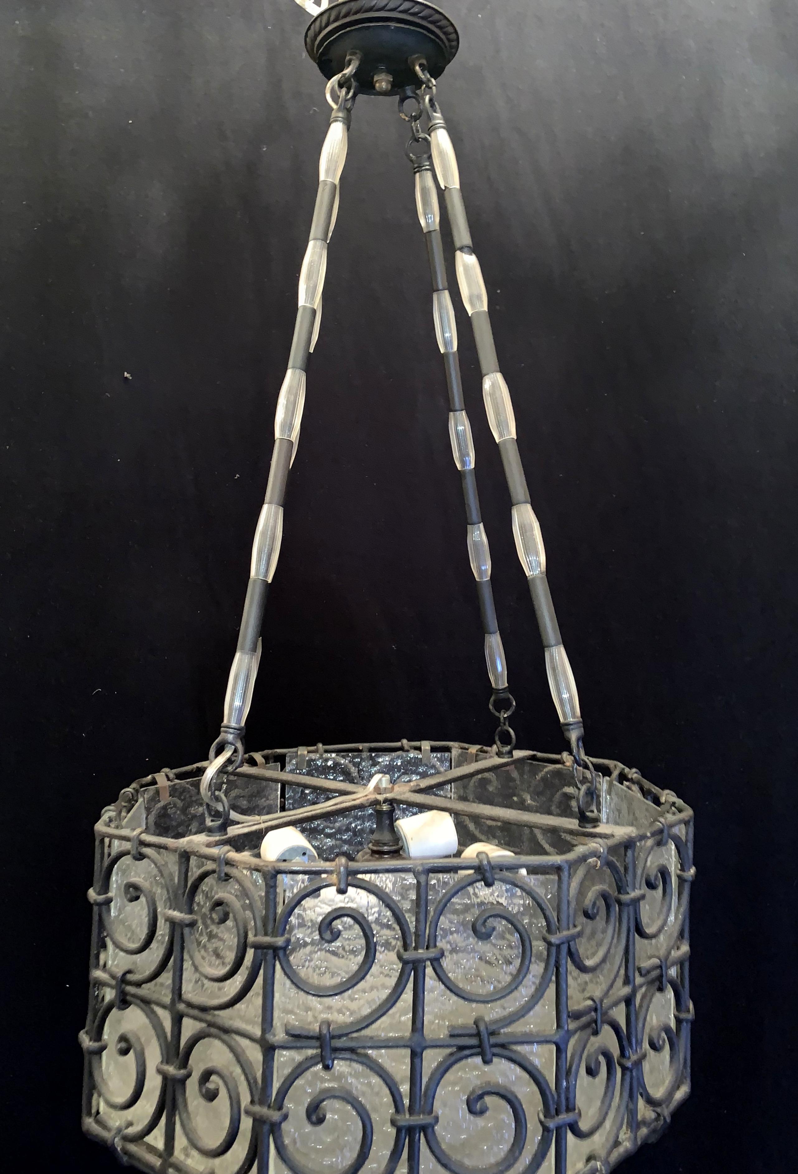 A wonderful Art Deco scroll iron frosted glass panel lantern fixture in the manner of Edgar Brandt.