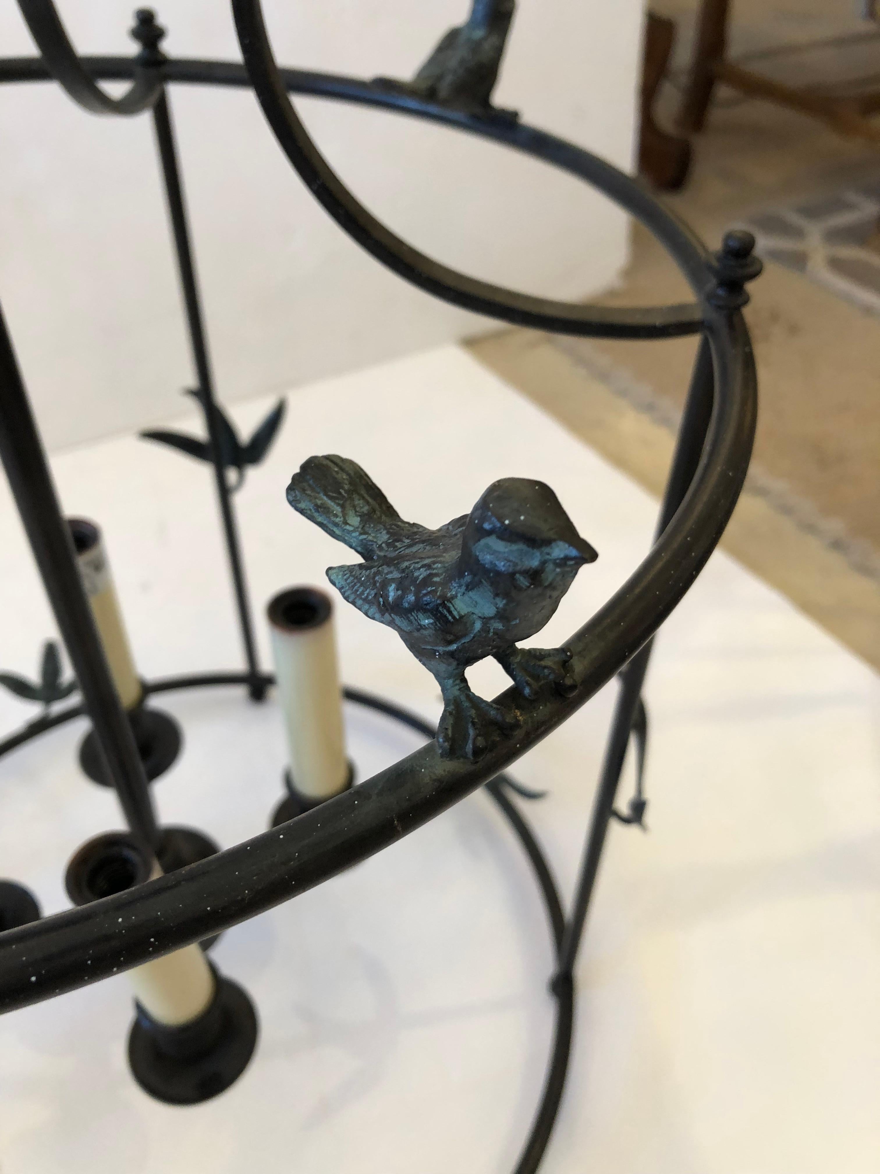 Charming black iron lantern having darling small birds perched around the top periphery and artful flourishes of foliage here and there.  There are four interior candle arms, 5 ft of chain and ceiling cap included.

NOTE:  Pair is available for $3900
