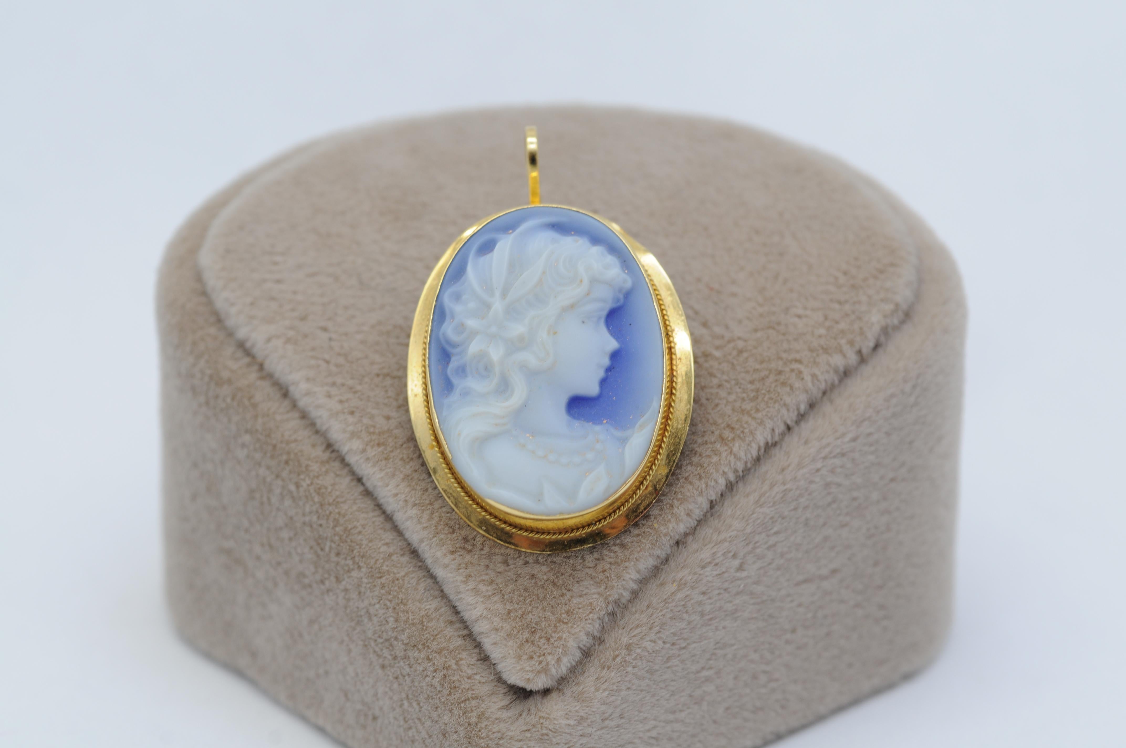 Behold the enchanting beauty of this exquisite blue 18k yellow gold cameo. This magnificent piece of jewelry features a stunning depiction of a beautiful woman, captured in intricate detail.

What sets this cameo apart is its versatility, offering