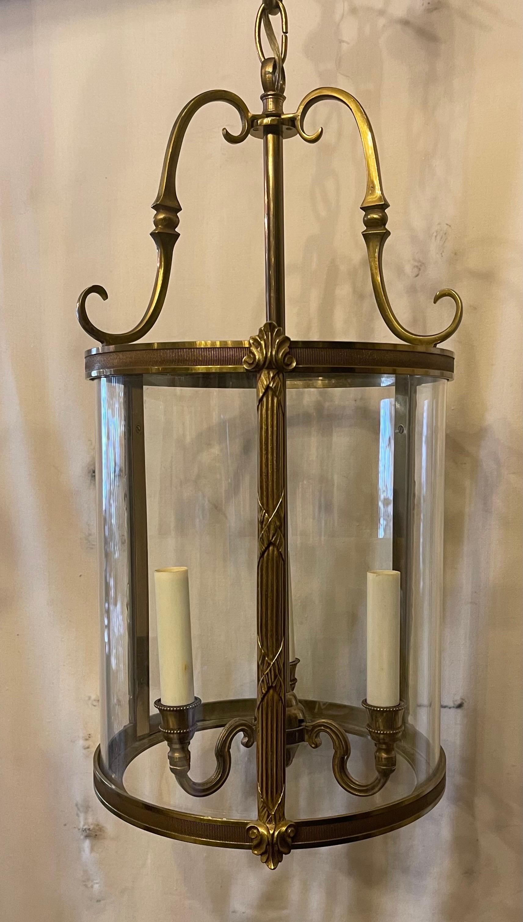 A wonderful French bronze readed x-pattern curved glass lantern neoclassical fixture having three candelabra lights inside, accompanied by chain canopy and mounting hardware.