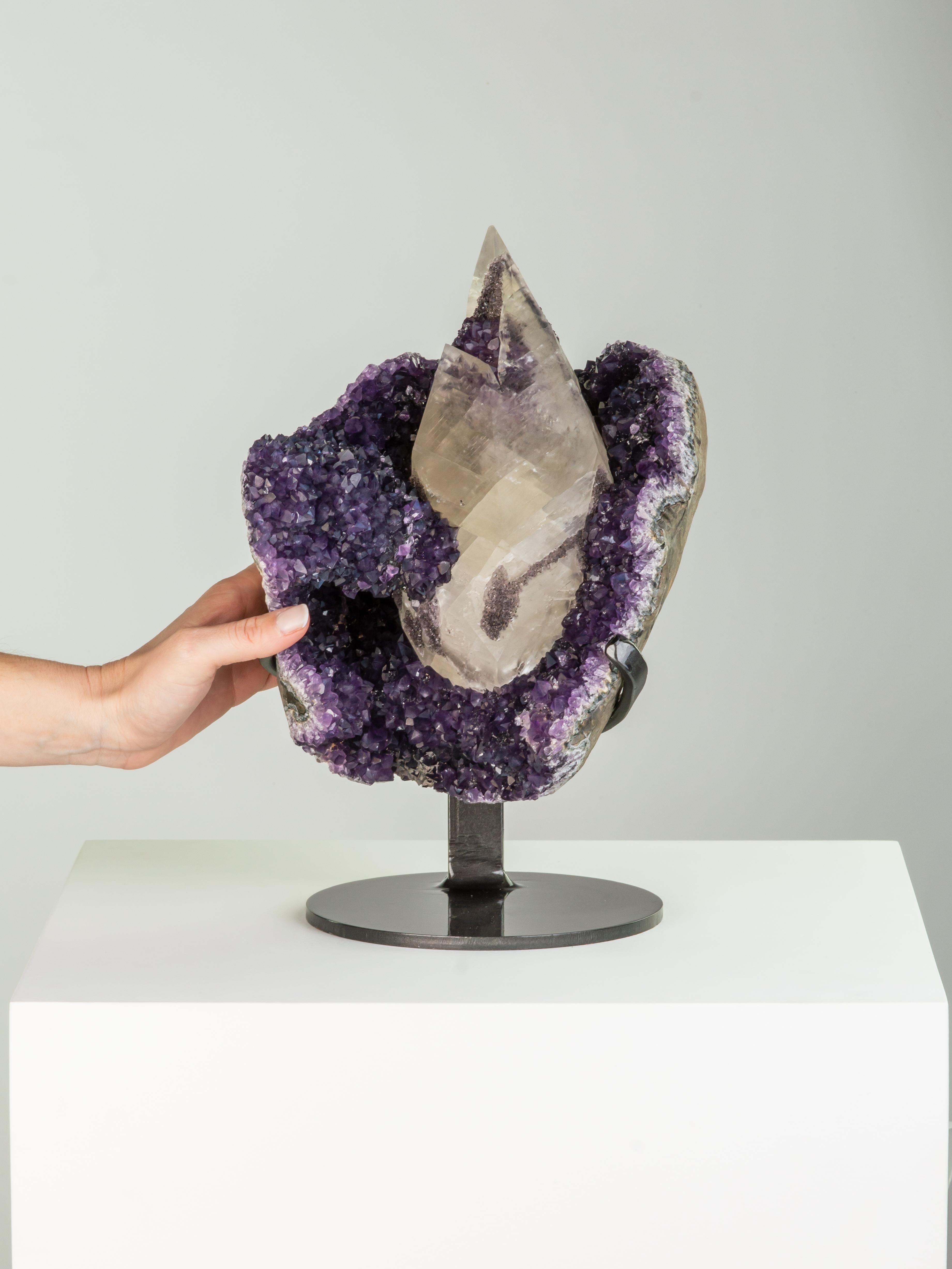 This stunning formation consists of a large pyramidal calcite on a bed of
deep purple amethyst. The split calcite with unusual epitaxial goethite
and a second generation of amethyst growth near the top. A wonderful
piece.

This piece was