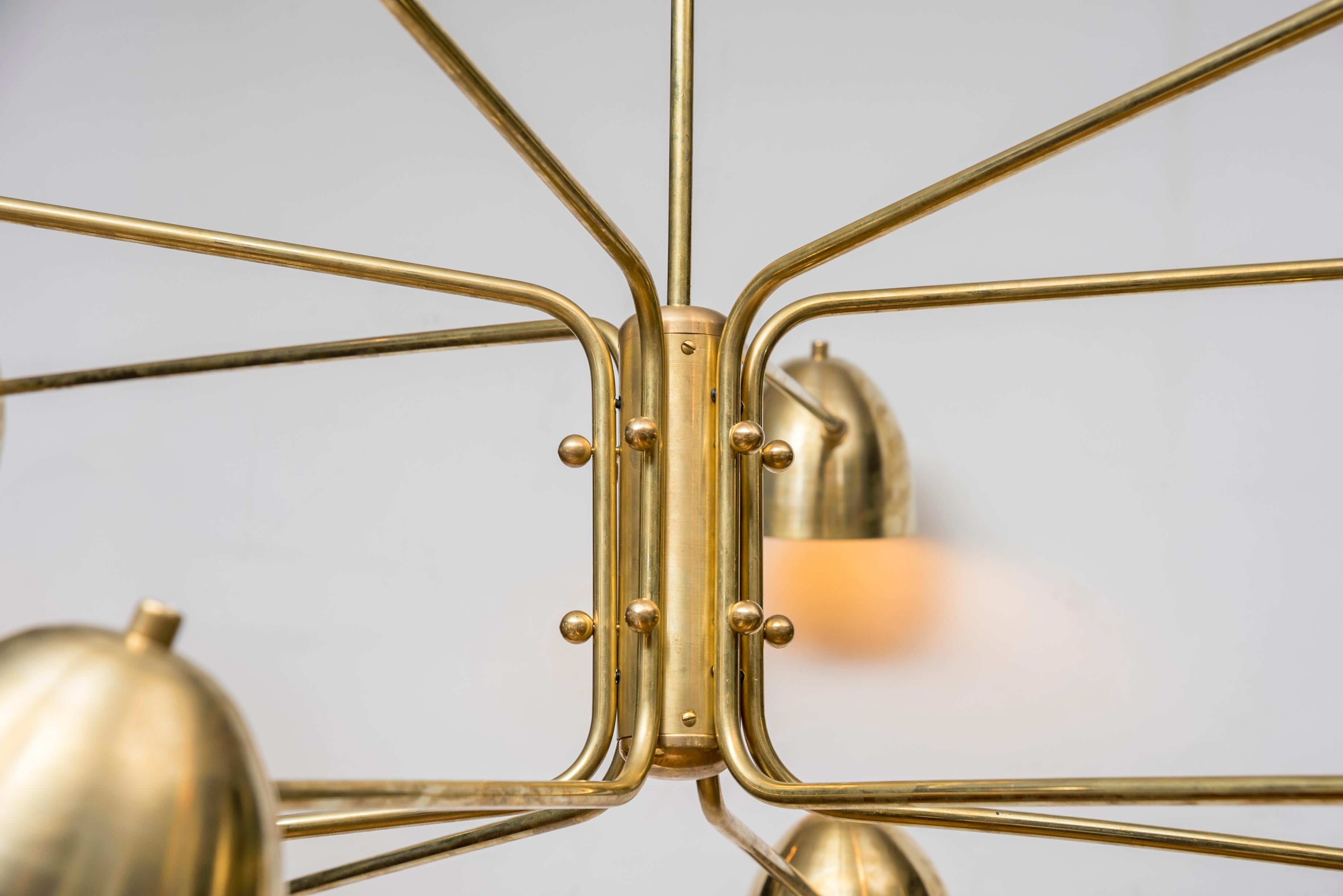 This contemporary brass chandelier is composed of 12 arms, each one holding a light bulb under a brass lampshade. This is an original creation by Studio Glustin, France, 2019.
