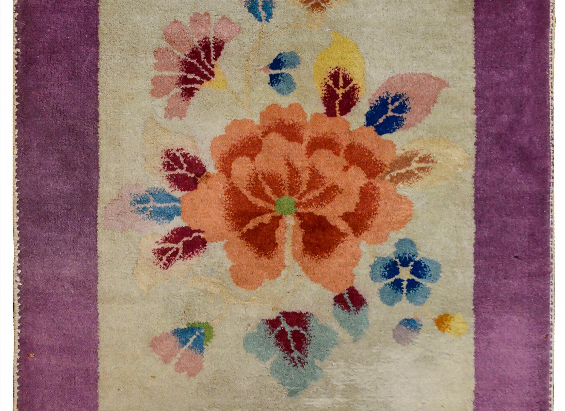 A wonderful early 20th century chinese Art Deco rug with a large coral colored peony woth more multicolored leaves and flowers on a gray background, surrounded by a wide violet border.