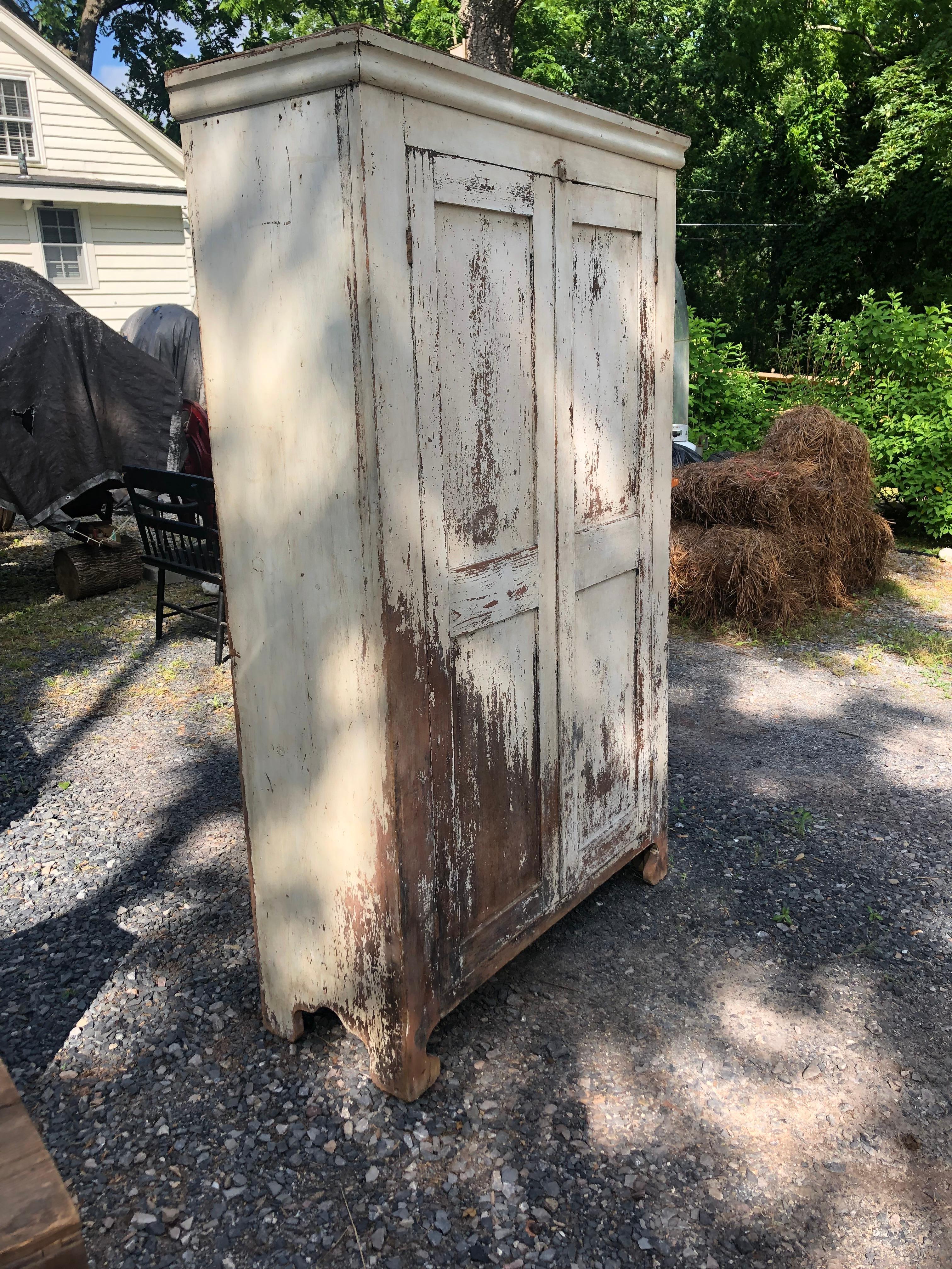 A wonderful painted and distressed country style Vermont wardrobe armoire having natural wood showing through aged white overcoat. Inside is outfitted with dowel and hooks on one side, more hooks on the other.
If you need closet space with