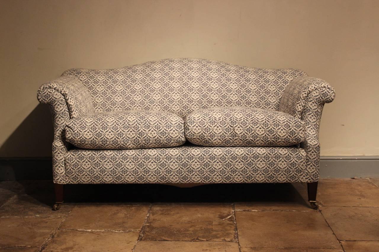 A very comfortable and elegant early 20th century Edwardian camel-back sofa by Howard & Sons, reupholstered in Howard & Sons monogrammed cotton. 

Measures: Seat height 56 cm.