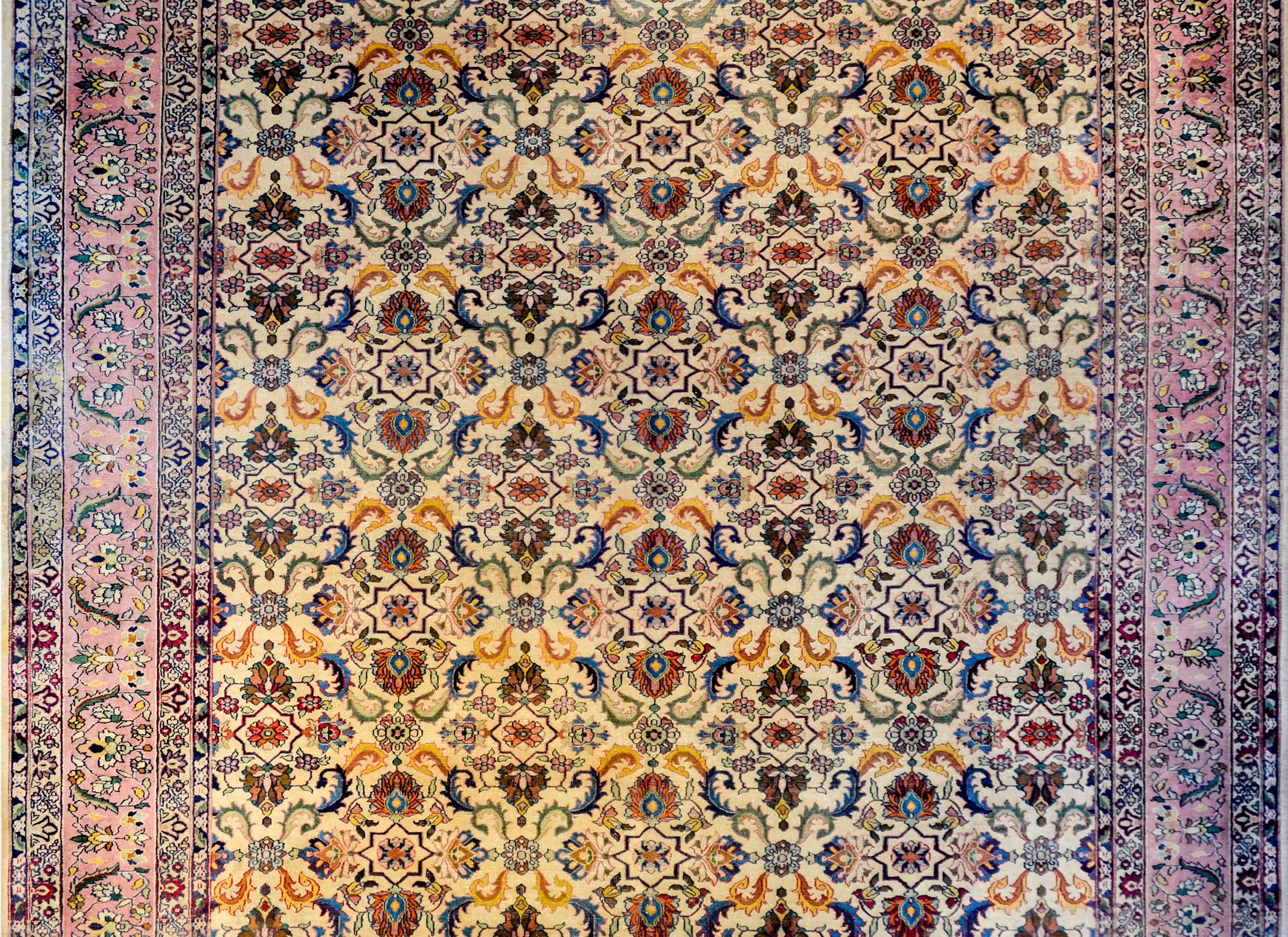 A wonderful early 20th century Indian Agra rug with a large-scale mirrored multicolored floral and vine pattern on a cream colored background. The border is wide with a central floral and vine patterned central strip flanked by matching petite flora