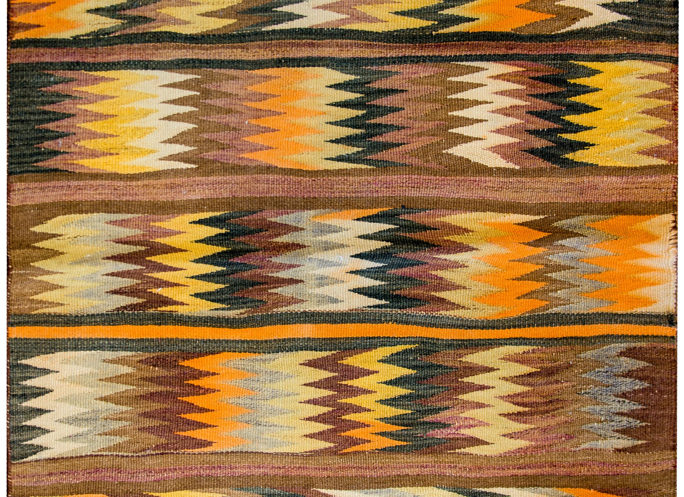 A wonderful early 20th century Persian Baluchi kilim rug with a bold multi-colored zigzag pattern arranged in stripes with solid colored stripes between.