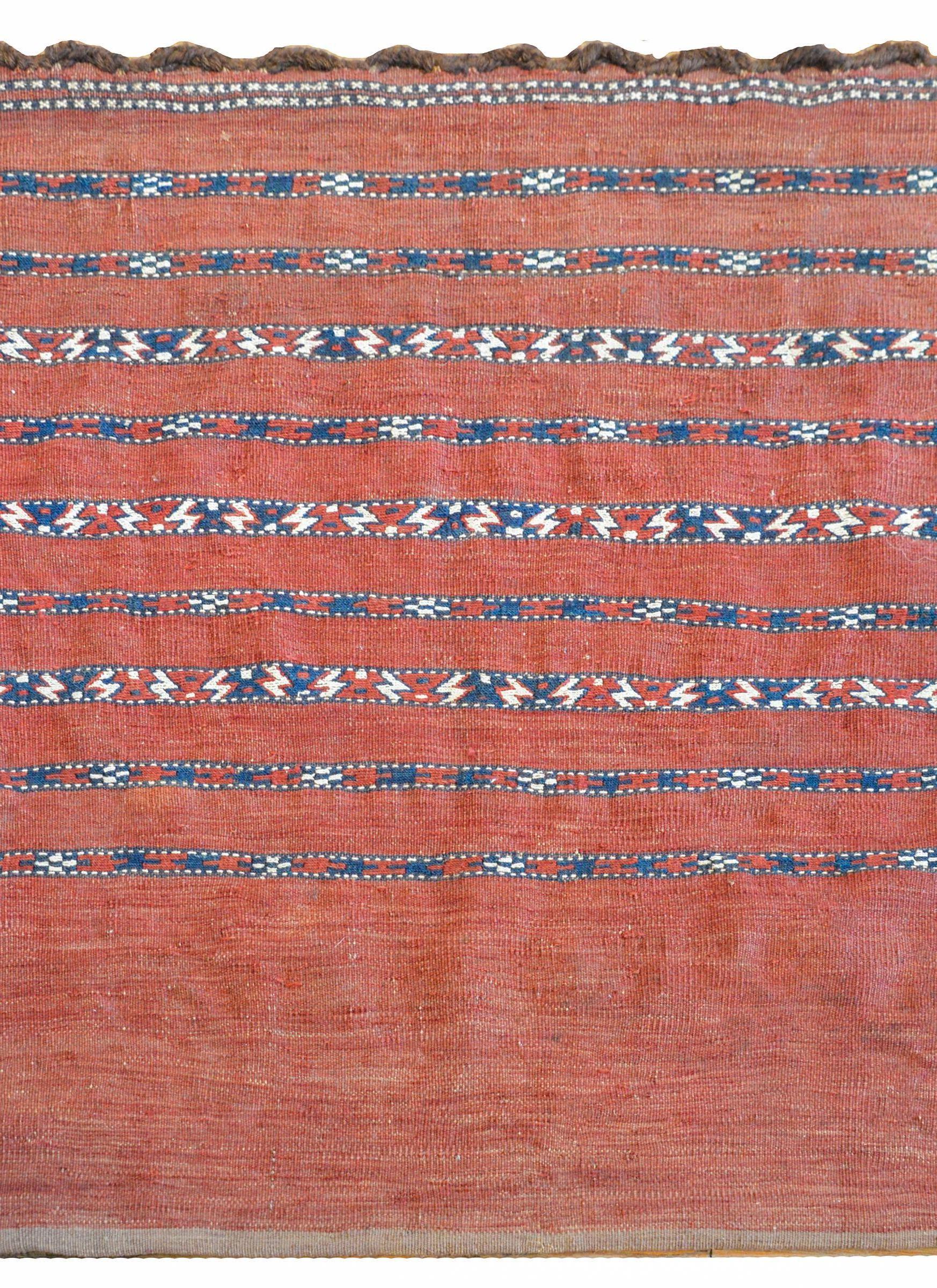 Ein schöner persischer Belutsch-Taschenteppich aus dem frühen 20. Jahrhundert mit karminrotem Grund und mehreren geometrisch gemusterten Streifen in Karminrot, Weiß und Indigo.