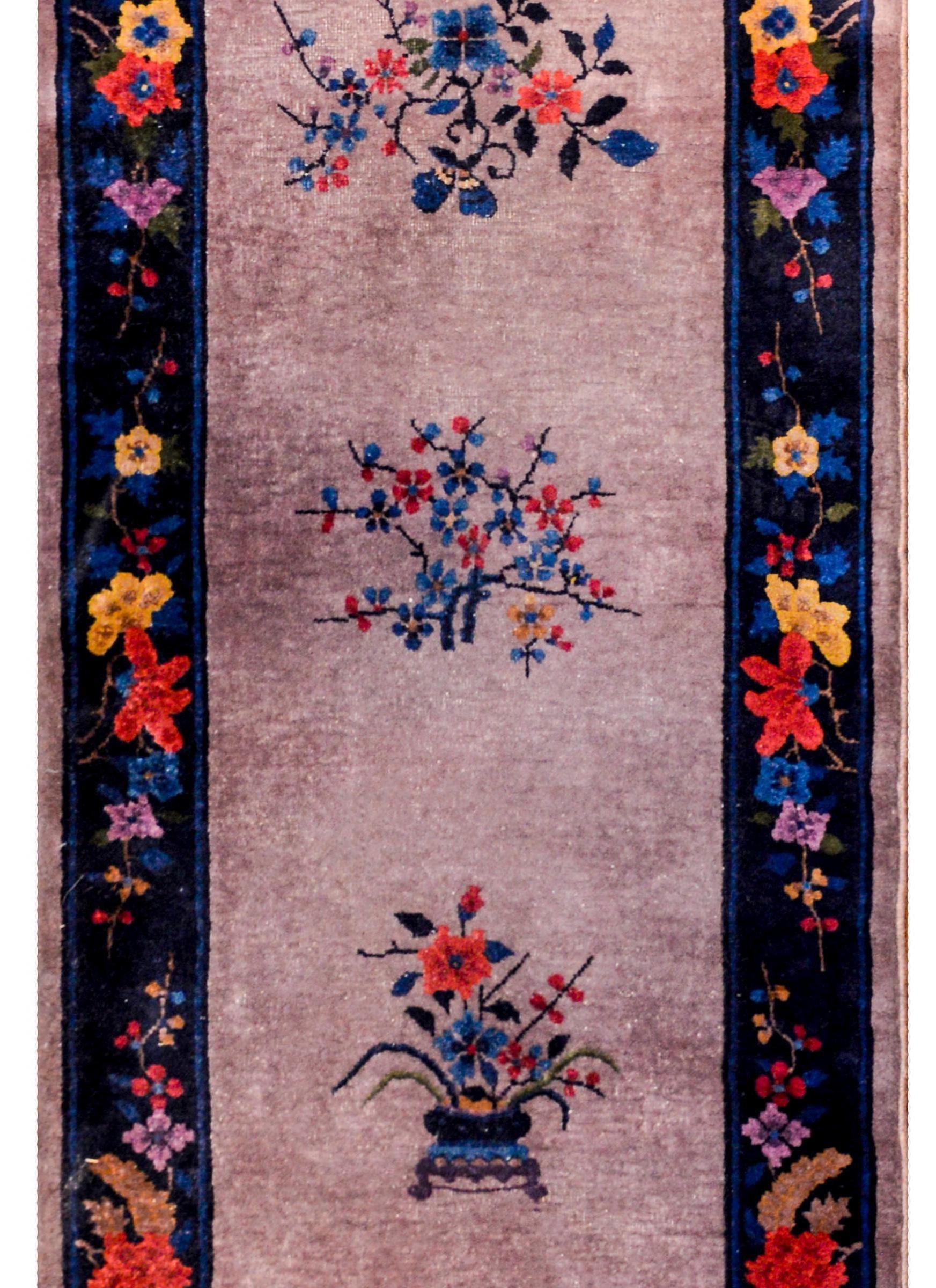 A wonderful early 20th century Chinese Art Deco runner with a beautiful grey field with several multicolored prunus blossom medallions, and potted blossoming branches on each end. The border is sweet, with a wide indigo stripe, with several