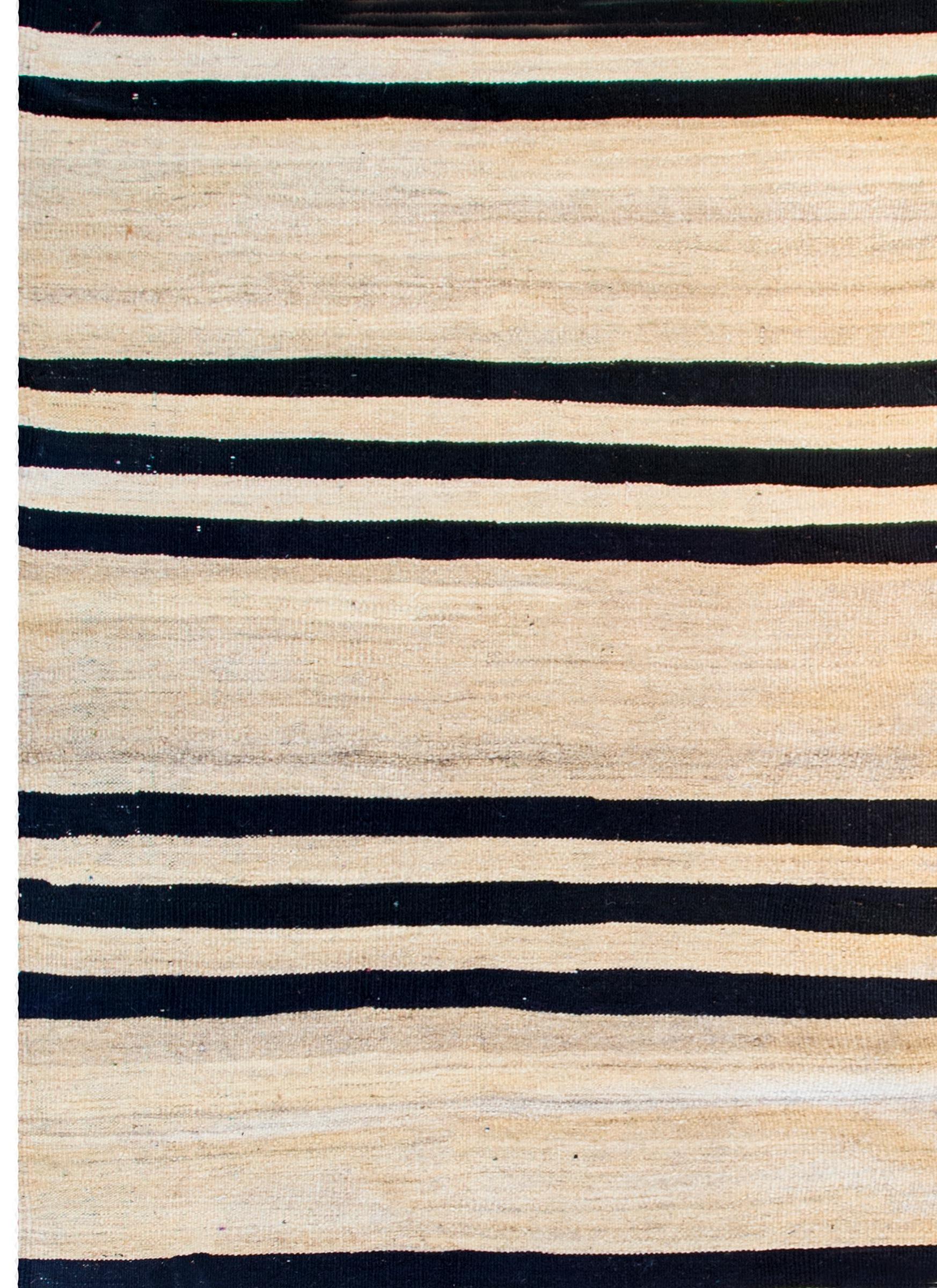 A wonderful early mid-20th century Persian Gabbeh Kilim runner with a bold horizontal stripe pattern with alternating black and natural wool stripes.