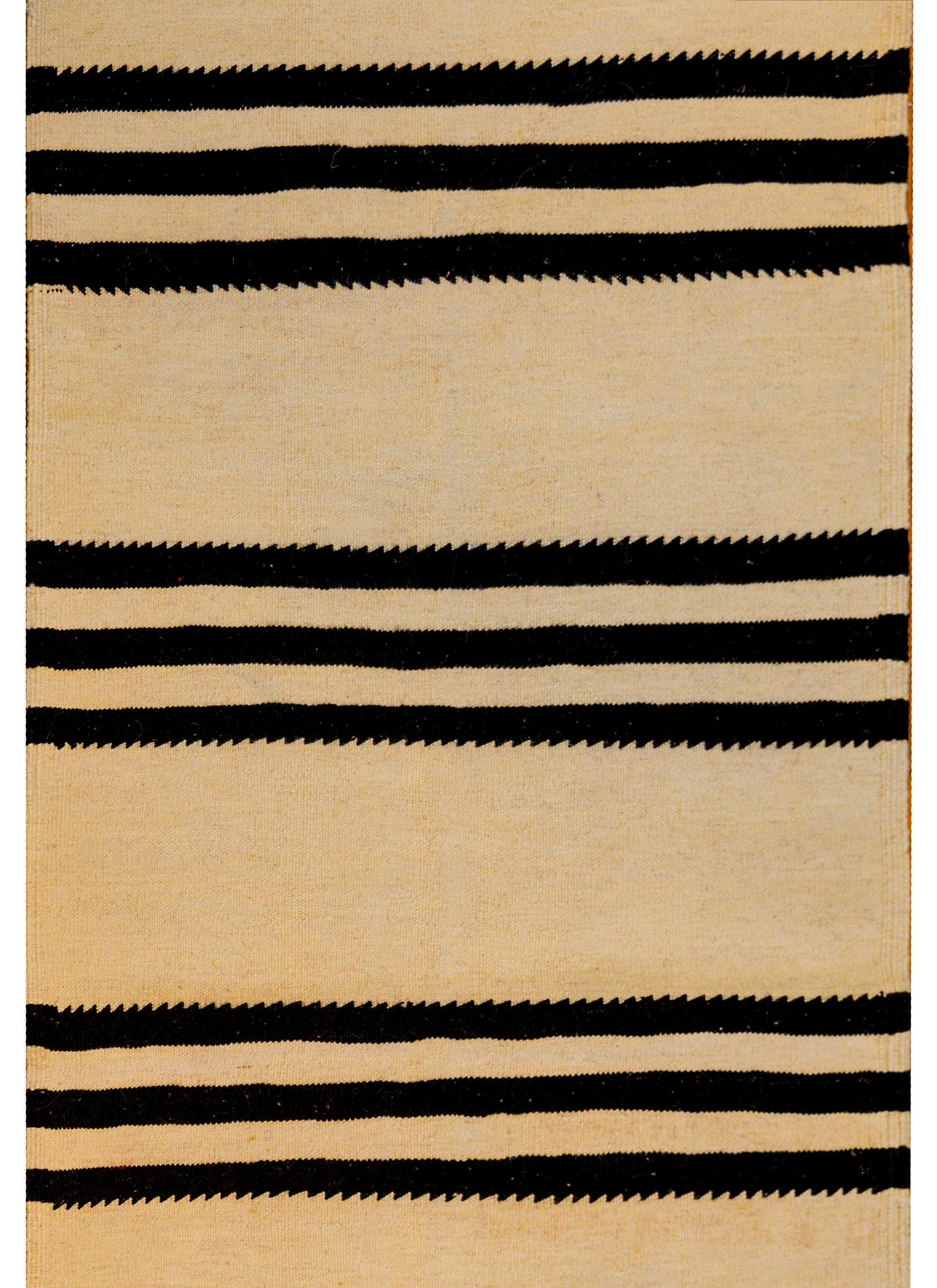 A wonderful early mid-20th century Persian Gabbeh Kilim runner with a bold horizontal black stripes with zigzag edges and natural wool stripes.