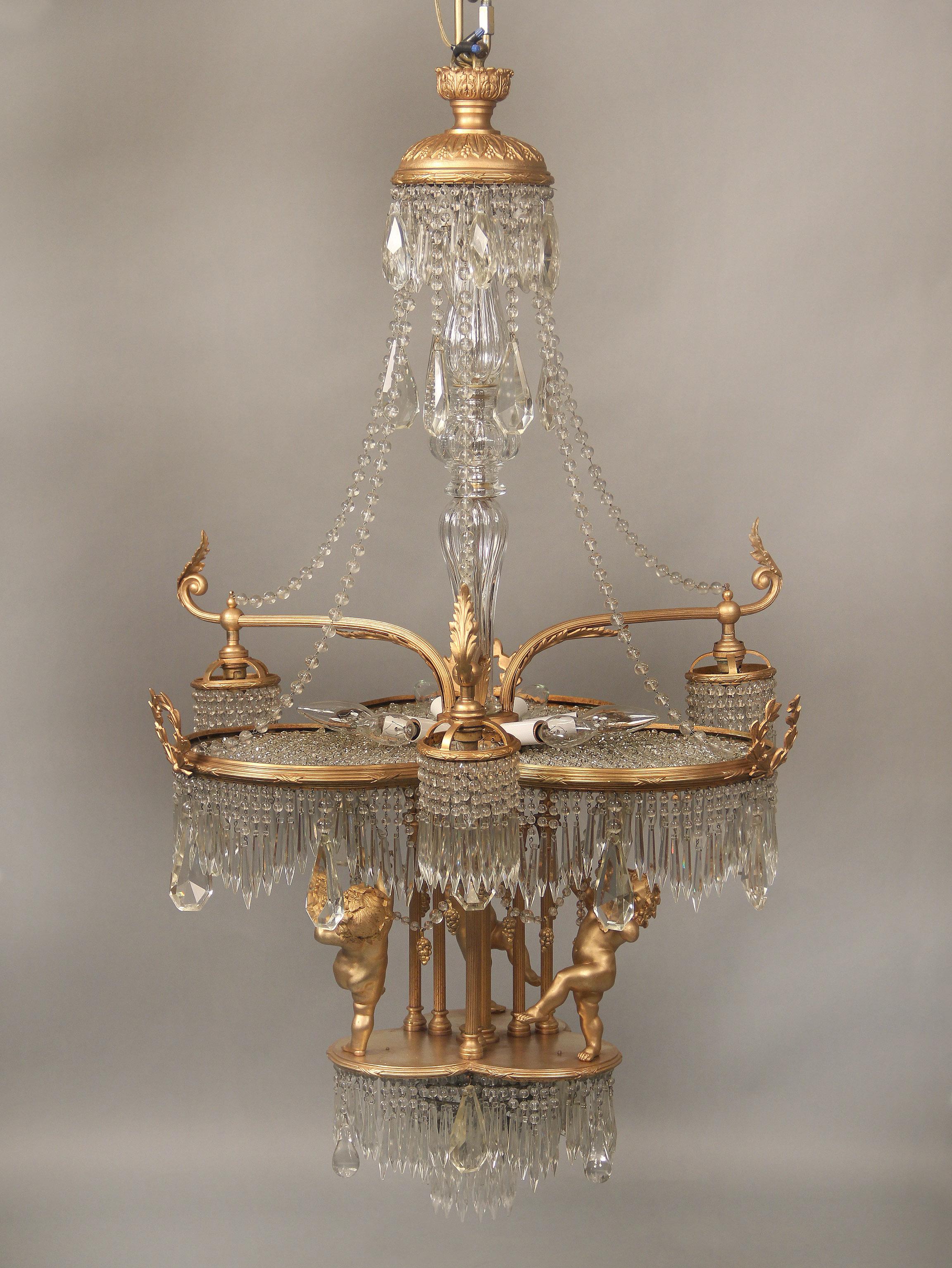 A wonderful early 20th century gilt bronze and crystal thirteen-light chandelier

multifaceted and shaped crystal, cut crystal central column with additional drop crystals, the “clover” shaped body with beaded floral crystals, the bottom with