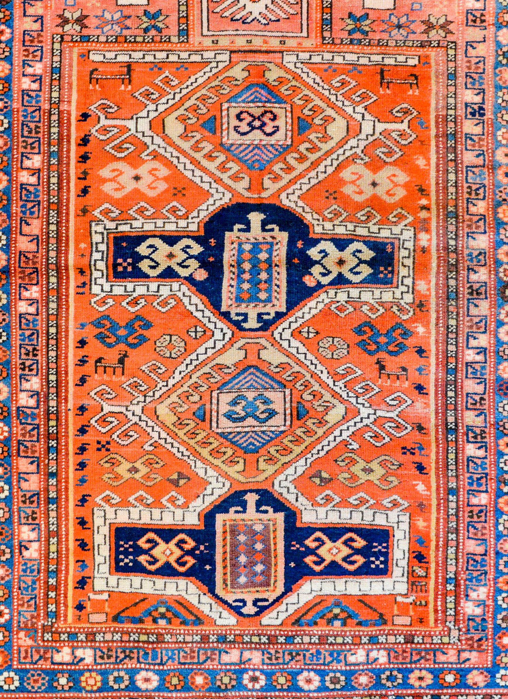 A wonderful early 20th century Persian Fachralo  Kazak prayer rug with four large stylized medallions with stylized flowers amidst a field of myriad stylized flowers with two hands on a crimson background surrounded by border containing multiple