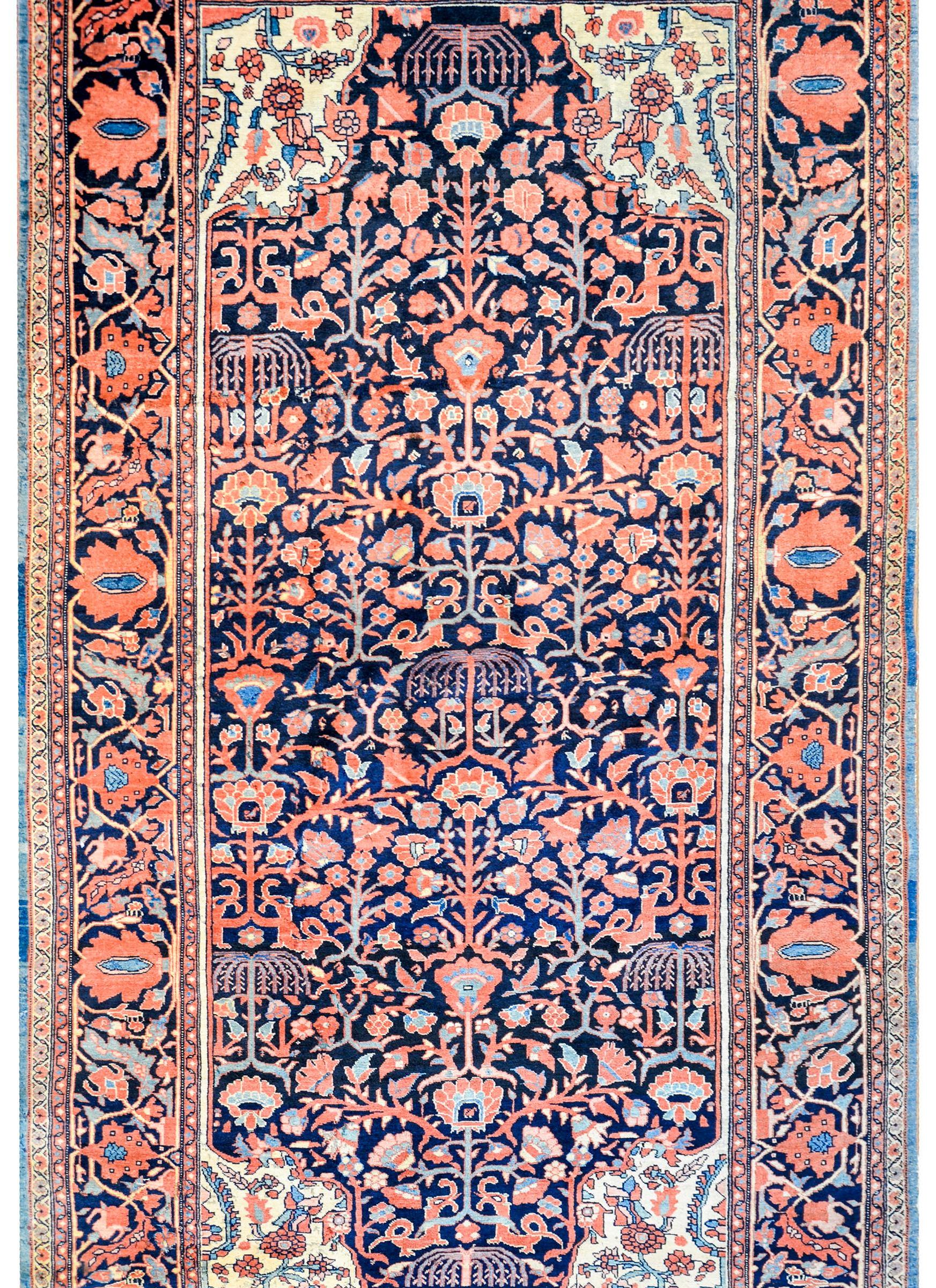 A wonderful early 20th century Persian Sarouk Farahan rug with an incredible all-over tree-of-life pattern woven in coral, salmon, light and dark indigo, and cream colored wool. The border is exceptional with a large scale wide central stripe
