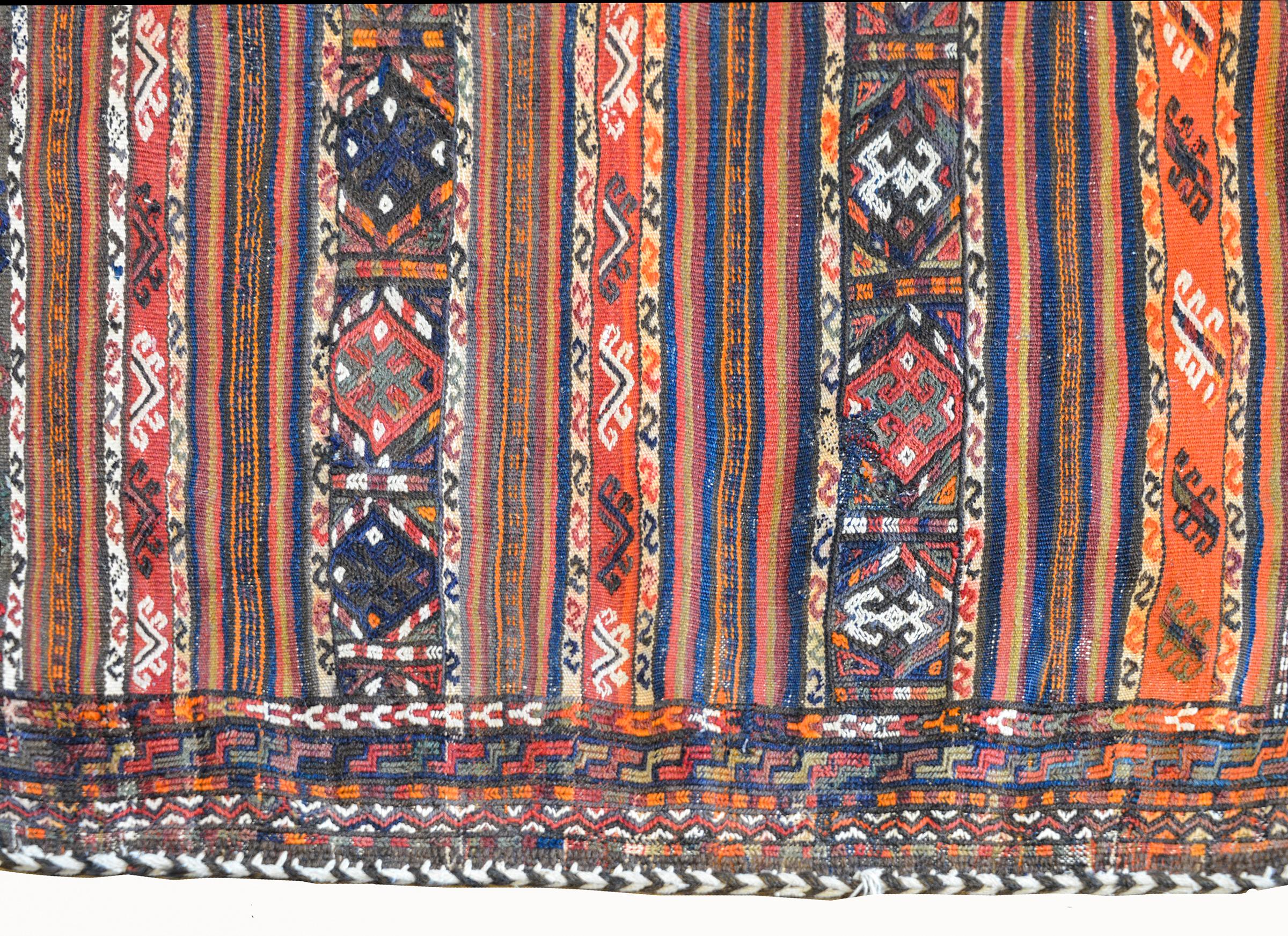 A wonderful early 20th century Persian Shahsevan bag face rug with several stylized floral patterned stripes on one side, and the reverse containing several multicolored solid stripes all woven in indigo, coral, crimson, black, and brown.
