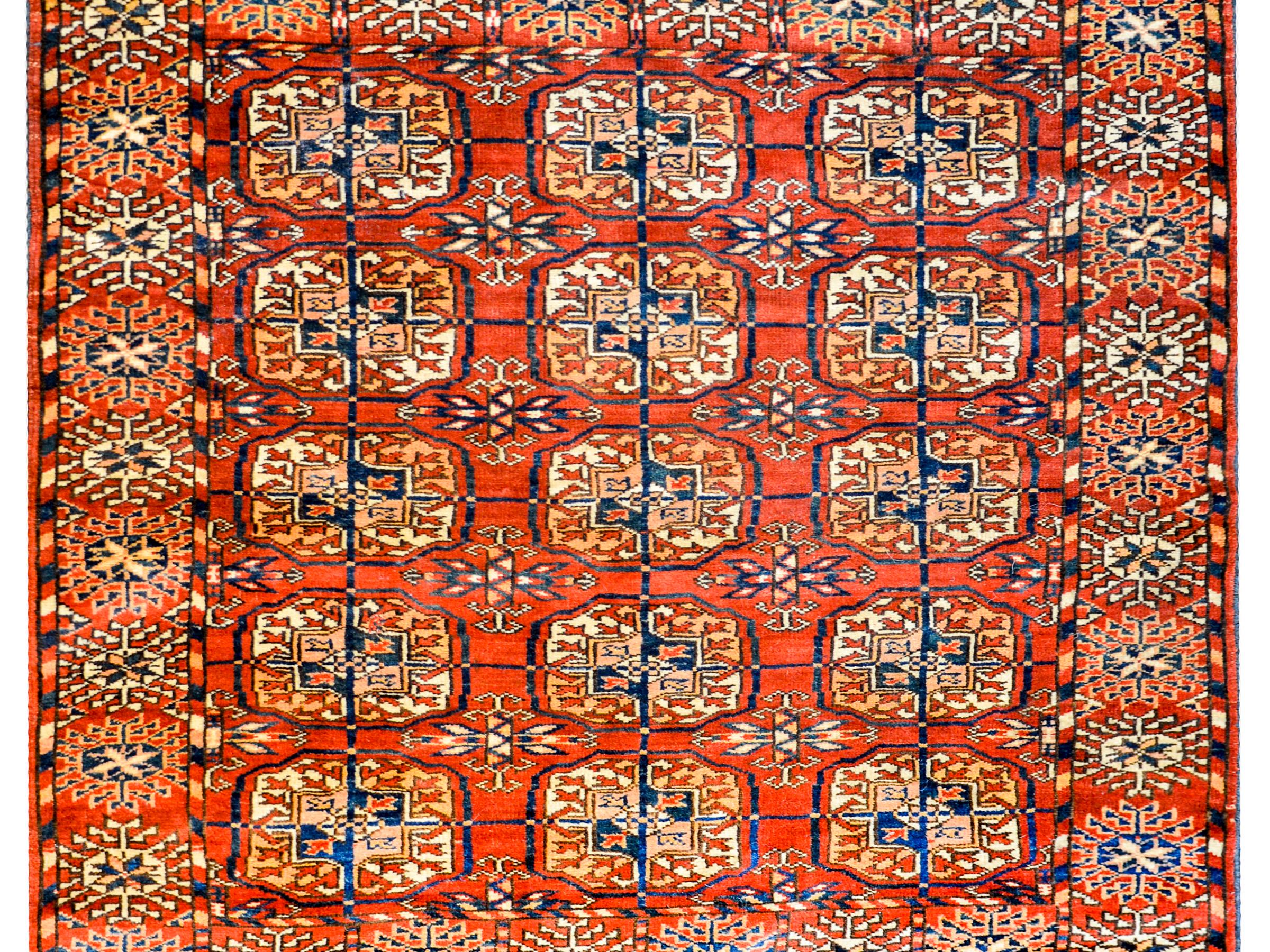 A wonderful early 20th century Persian Tekeh rug with all-over medallions woven in crimson, indigo, white and cream colored wool, on a crimson background. The border is complex with a fantastic stylized floral pattern surrounding the field, with a