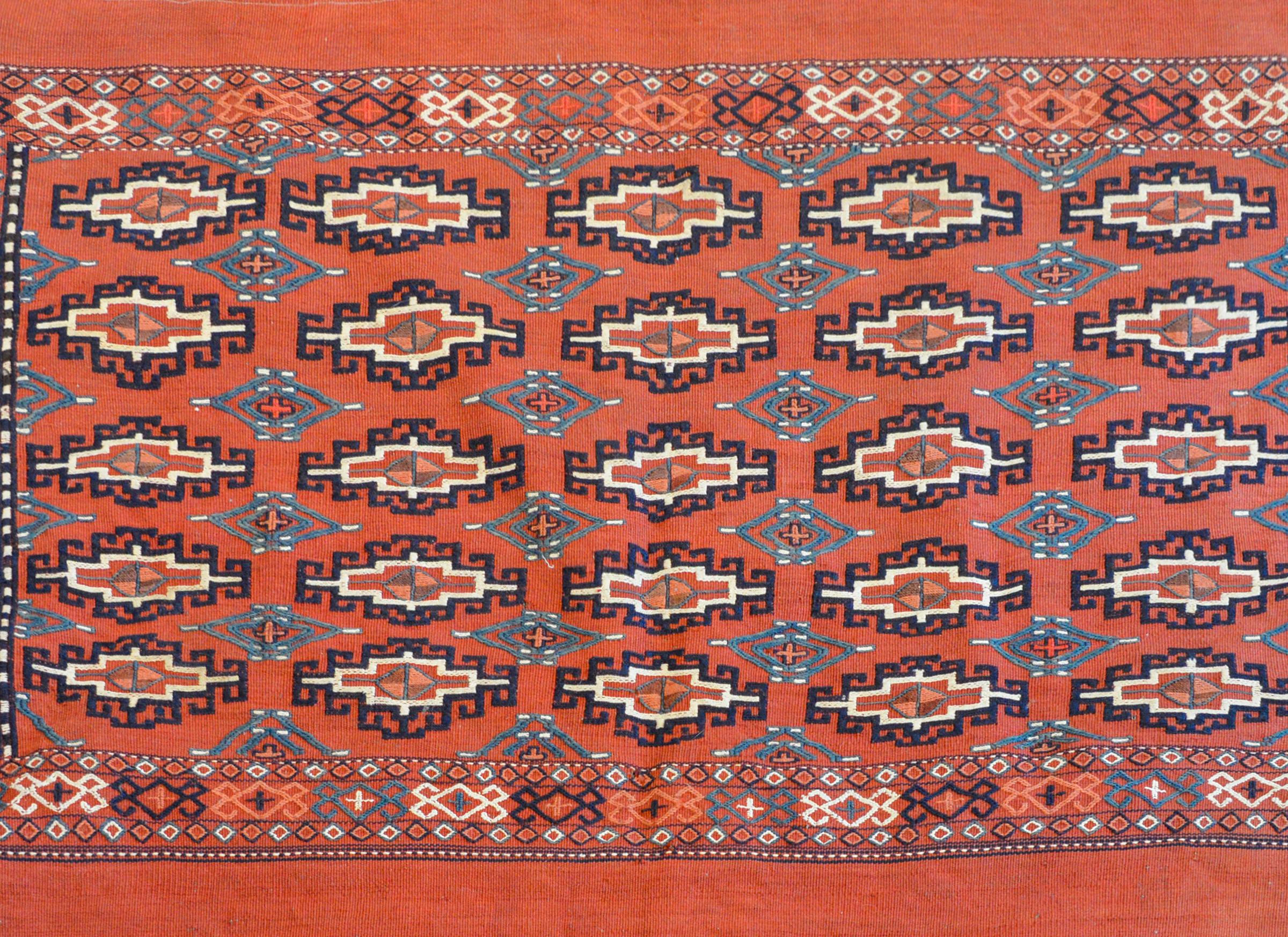 A wonderful early 20th century Persian Turkoman flat-weave bag face with embroidered diamonds and across the field woven in teal, indigo, white, orange, and green wool on a scarlet background.