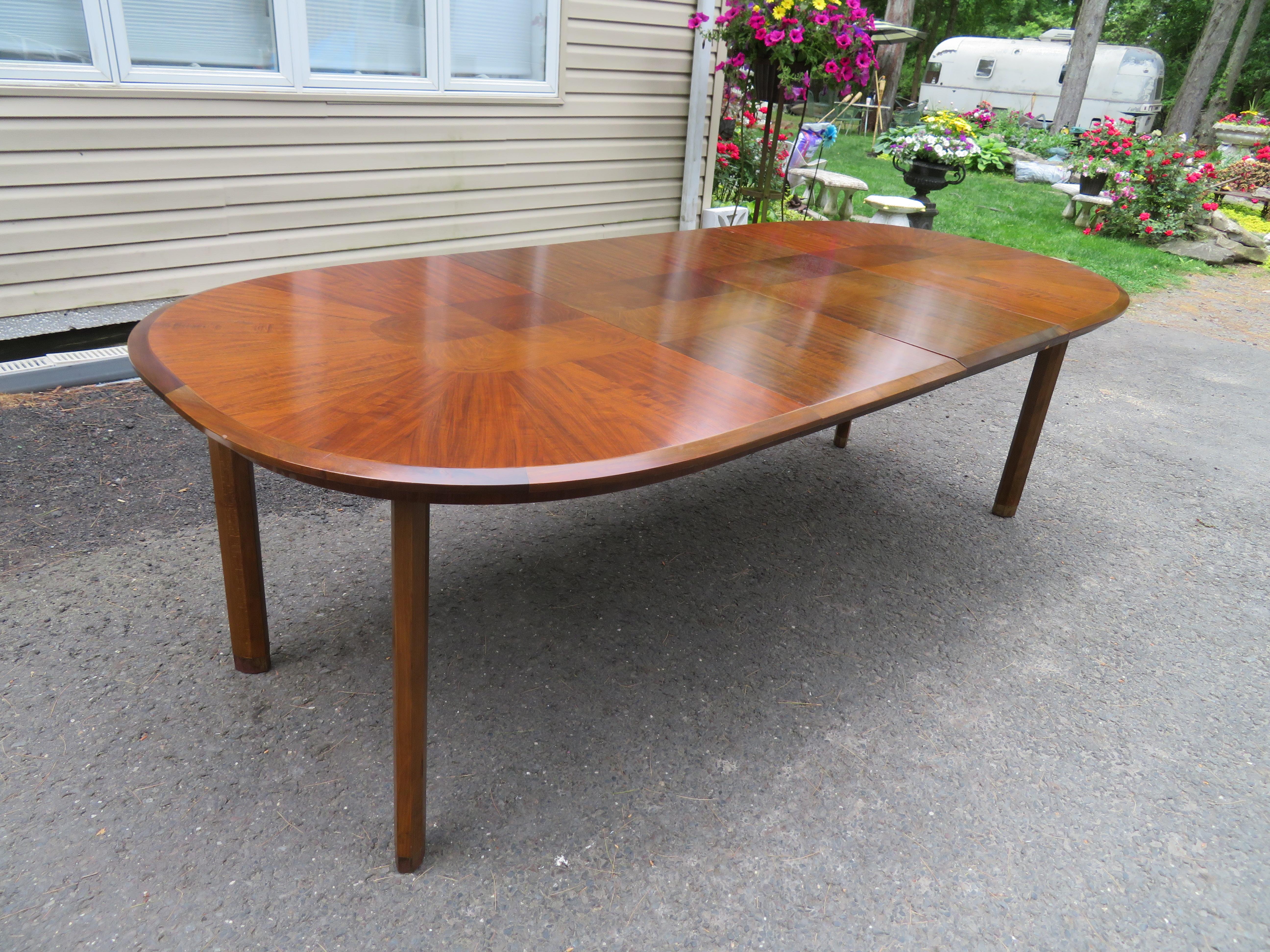 Mid-Century Modern Edmond J Spence walnut bevelled edge racetrack dining table made in Sweden. This table is very well crafted and of high quality. We love the thick bevelled edge along with the faceted chunky legs with brass sabots-very stylish