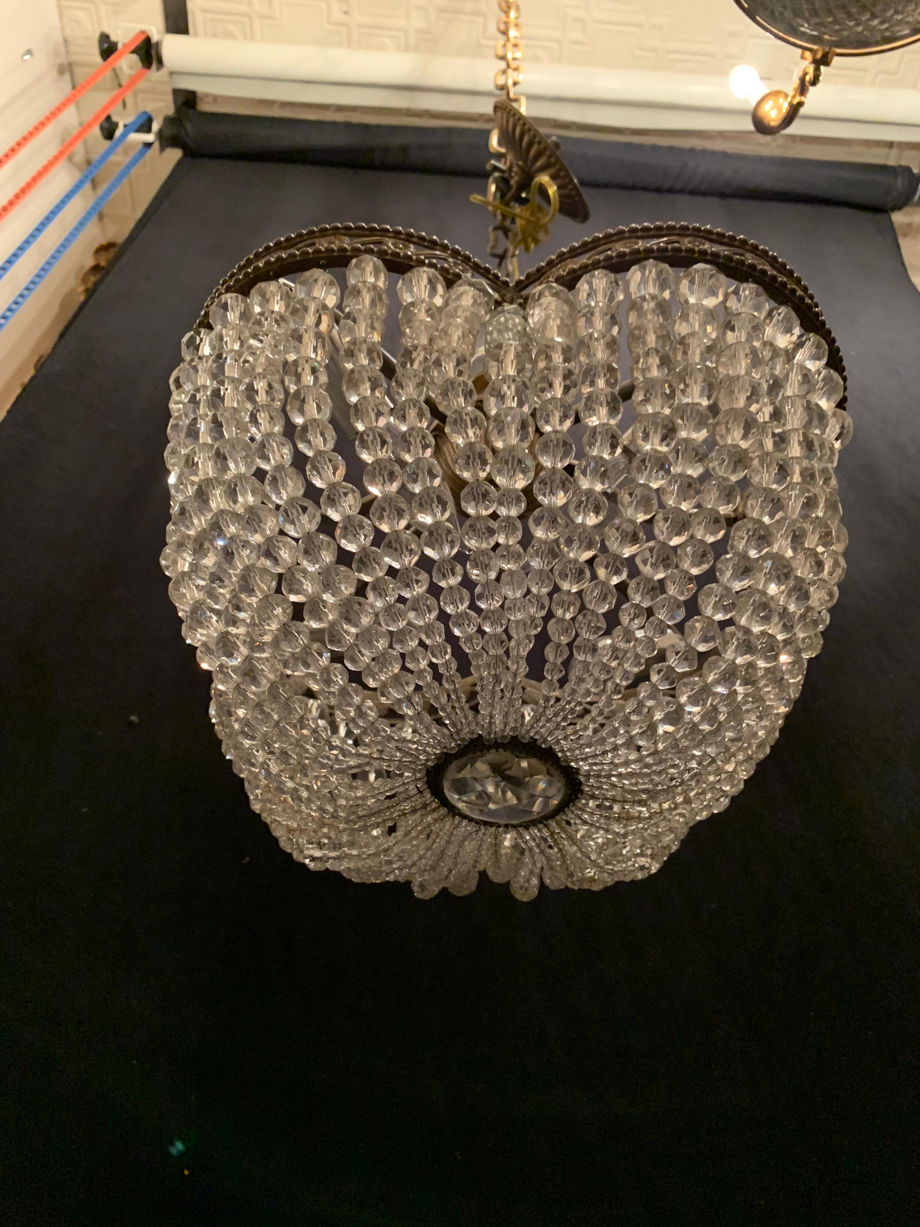 A wonderful French bronze and crystal beaded clover shaped open work ormolu basket form chandelier with 4 candelabra sockets recently rewired with new sockets and comes with canopy and chain as well as mounting hardware for installation.