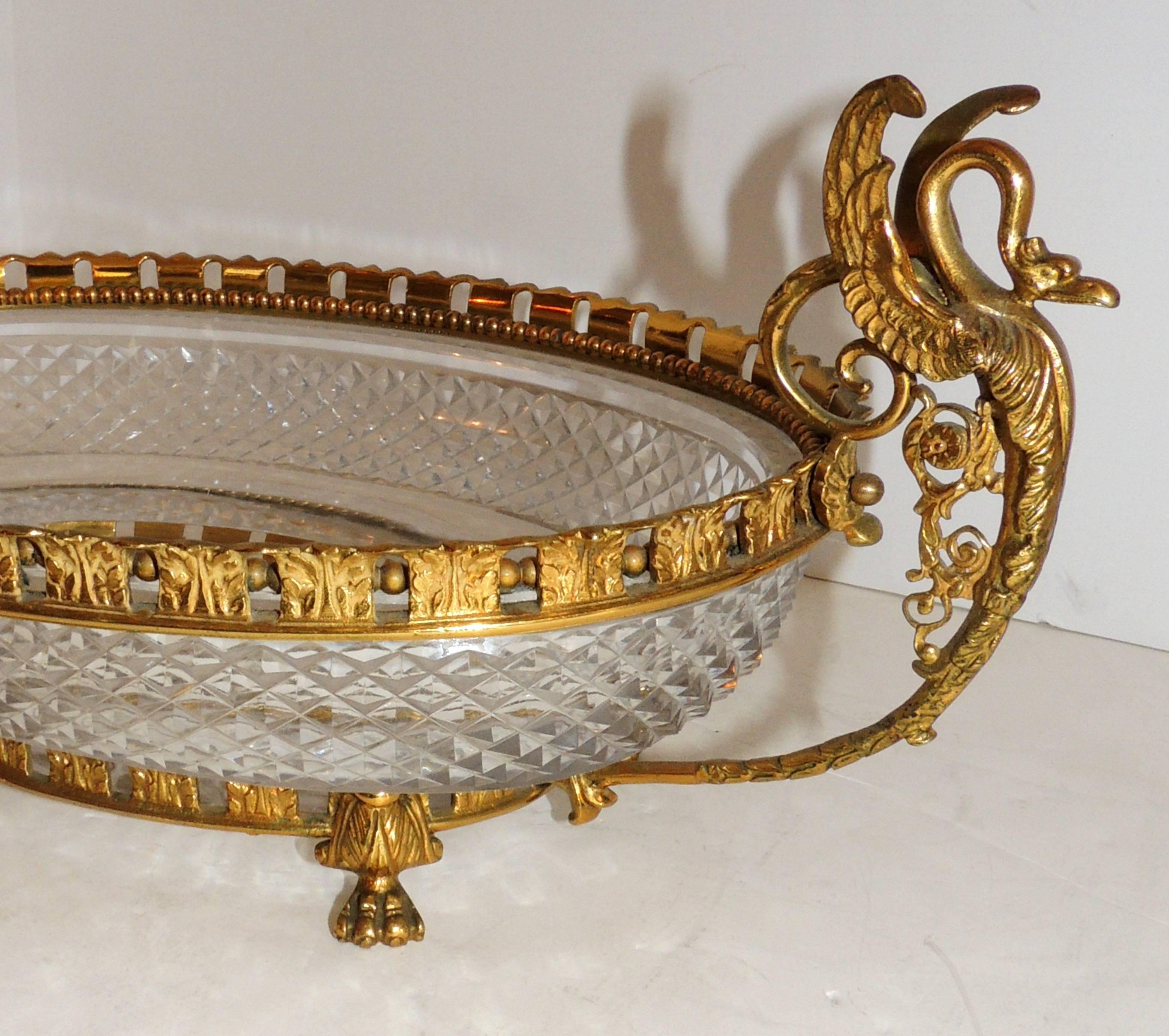 A wonderful French neoclassical gilt bronze and diamond cut crystal oval centerpiece 
with swan handles in the manner of Baccarat, circa 1940s.

