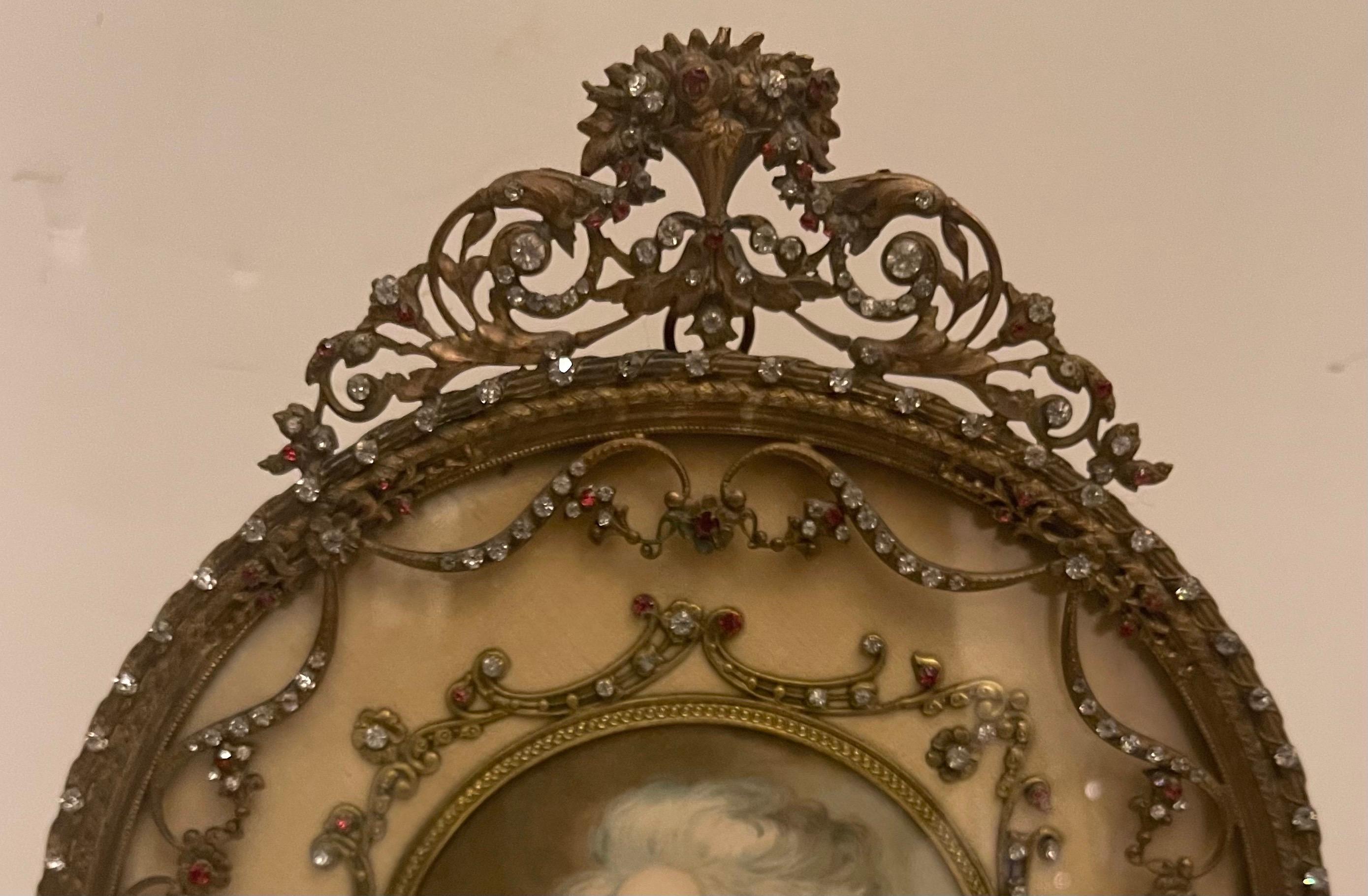 Splendida cornice francese in bronzo ormolu e gioiello montata in stile Luigi XVI con corona di bouquet e festoni traforati.