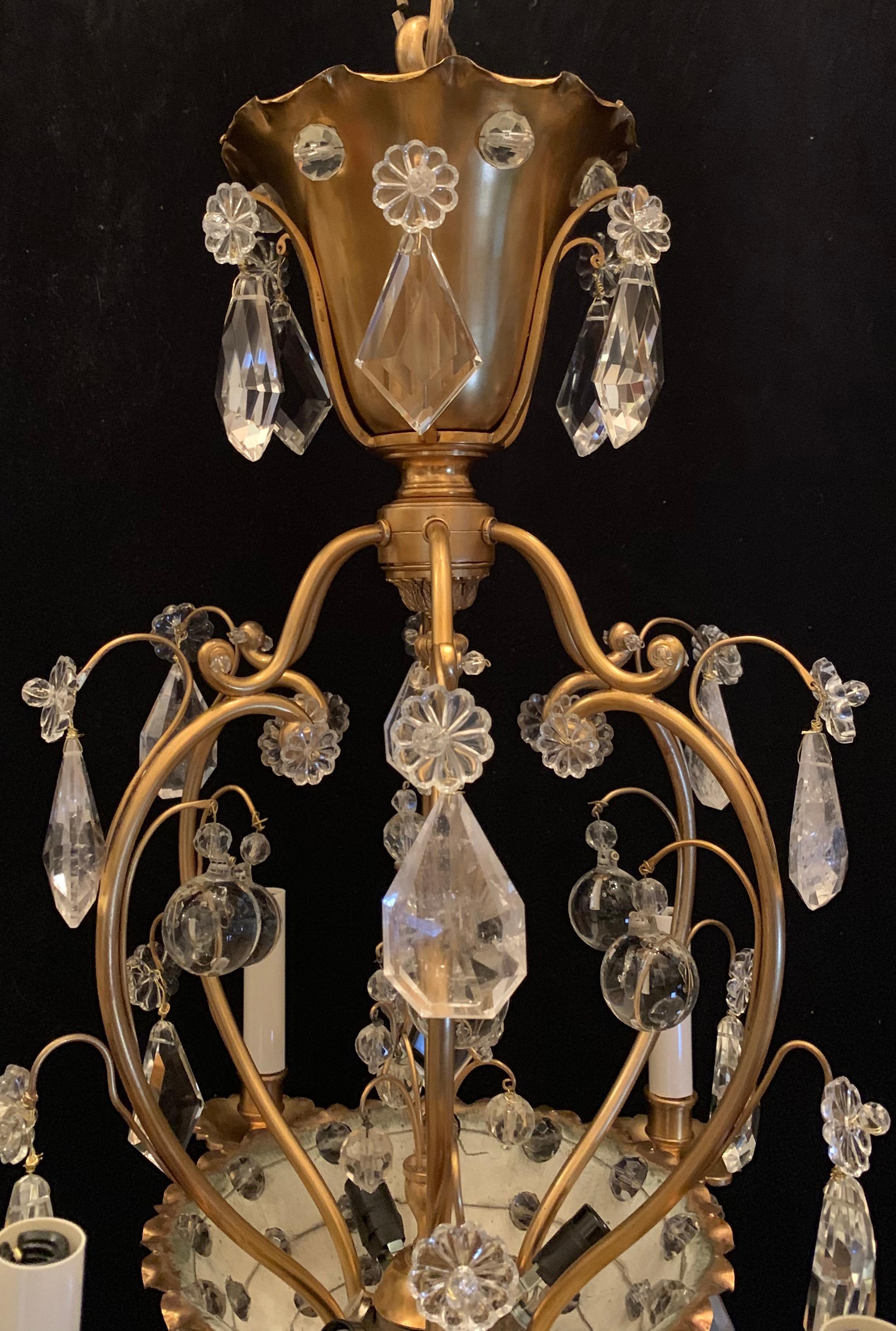 A wonderful French bronze and rock crystal chandelier in manner of Baguès with 6 arms in a basket form is adorned with beads and a center piece that lights up with 3 interior lights for a total of 9-light.
This fixture has completely been rewired