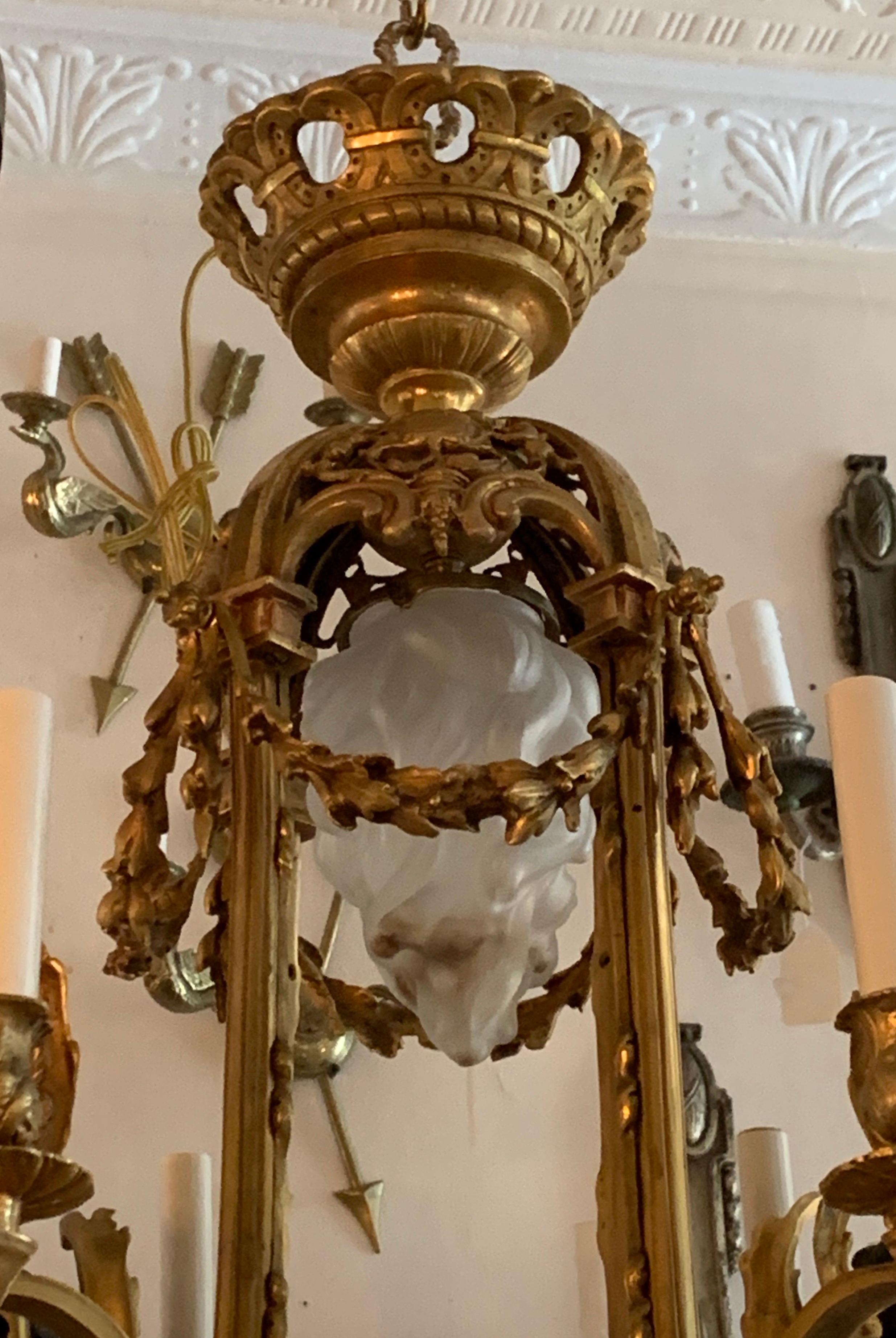 A wonderful French cherub / putti neoclassical doré & patinated bronze nine-light chandelier with 4 cherubs each having two candelabra lights and a center flame frosted glass shade.
