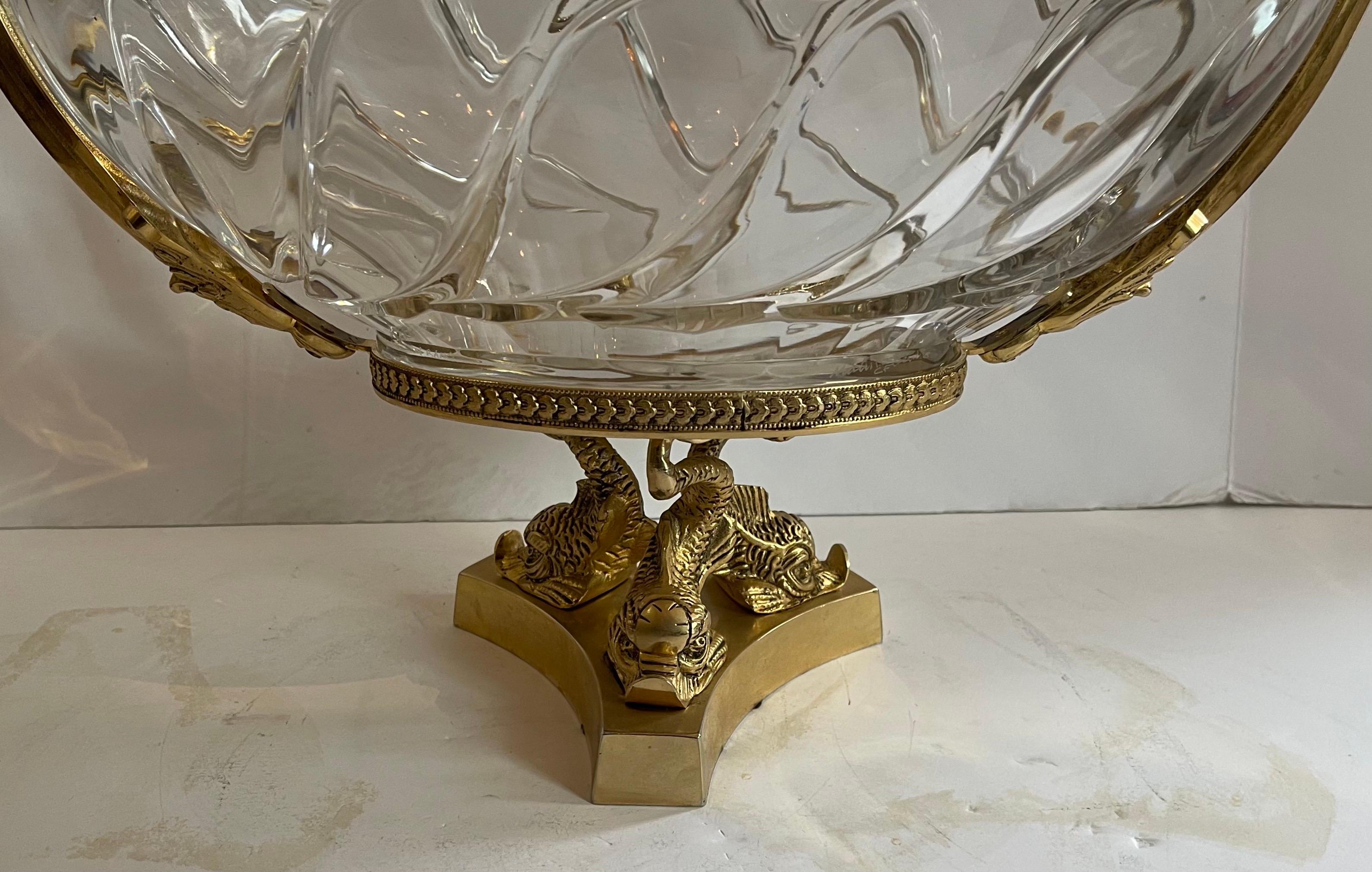 A wonderful large French doré bronze centerpiece with three dolphins on the pedestal supporting an oval crystal bowl with two lovely swans in flight on each side. The faceted fine cut crystal insert with star burst bottom add to the elegance of this