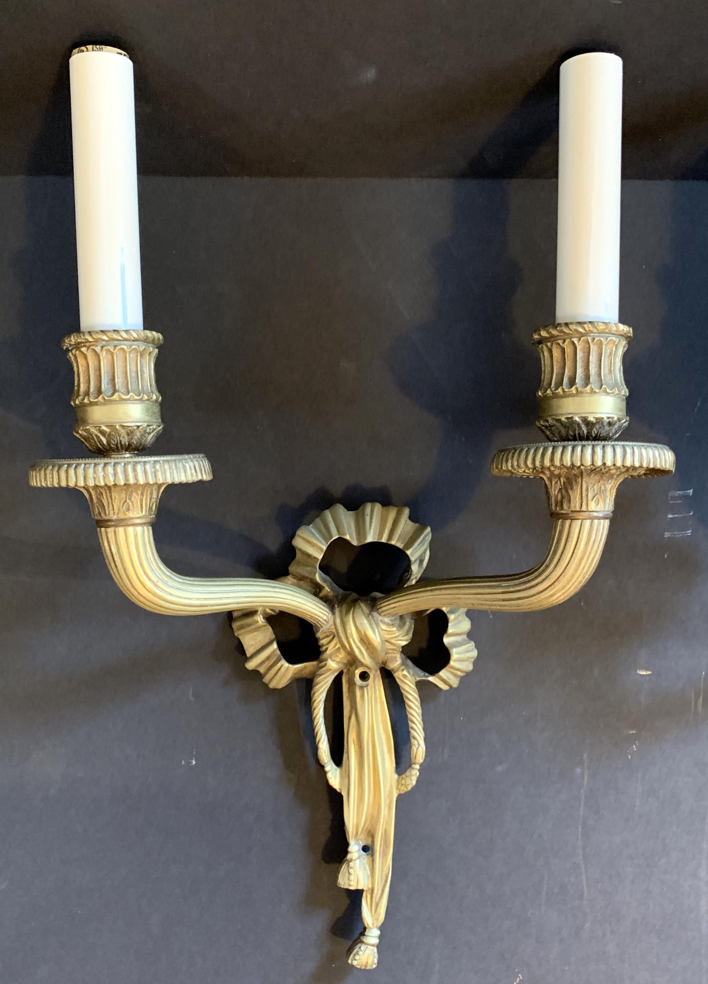 Une merveilleuse paire d'appliques à deux bras en bronze doré français, avec ruban et glands, à la manière de Caldwell.
 