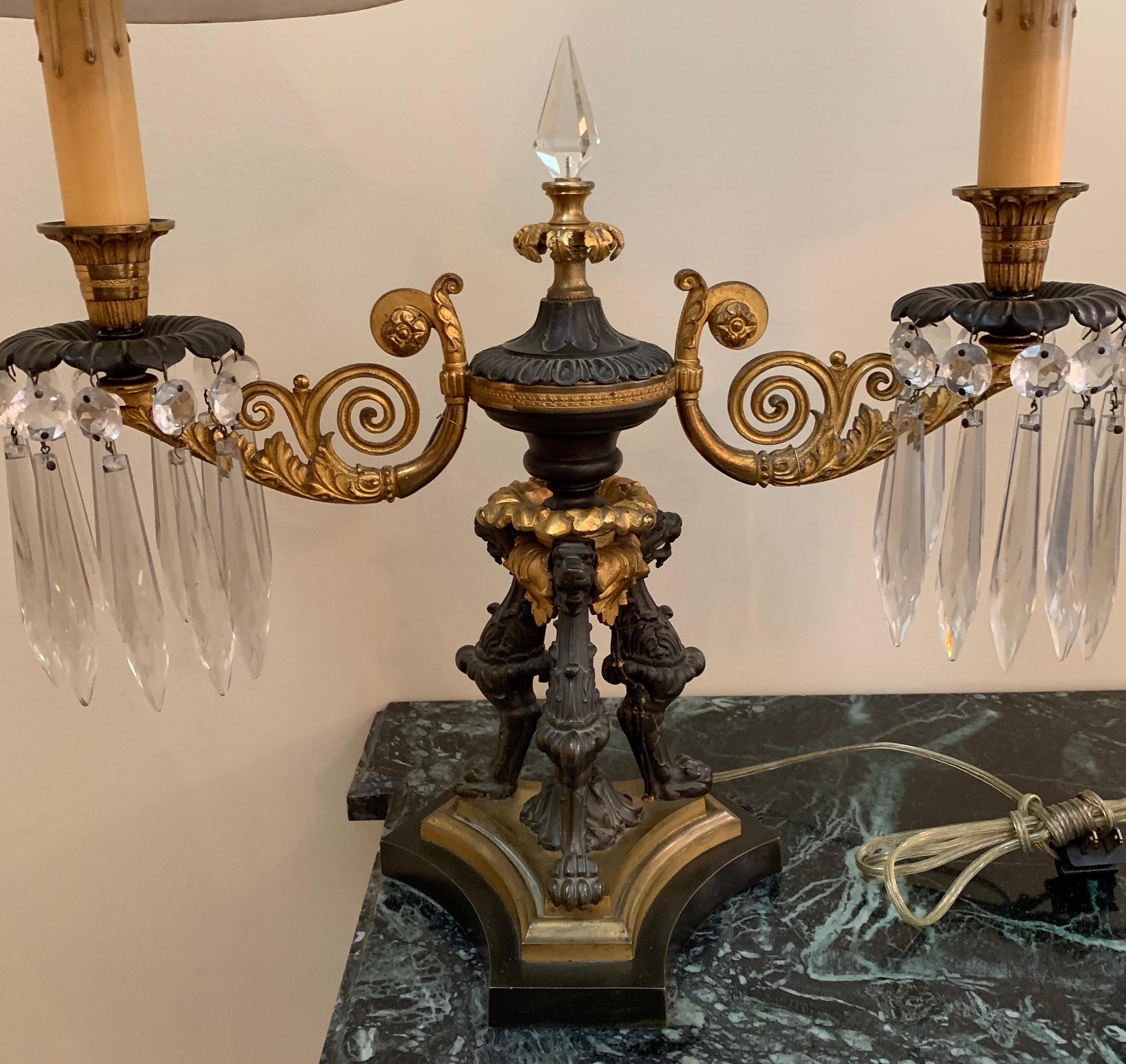 A wonderful French Empire/Regency gilt and patinated two-tone bronze boullite lamp with two tone shades and adorned with a crystal center spike and crystal drops on each arm, in the manner of Caldwell.