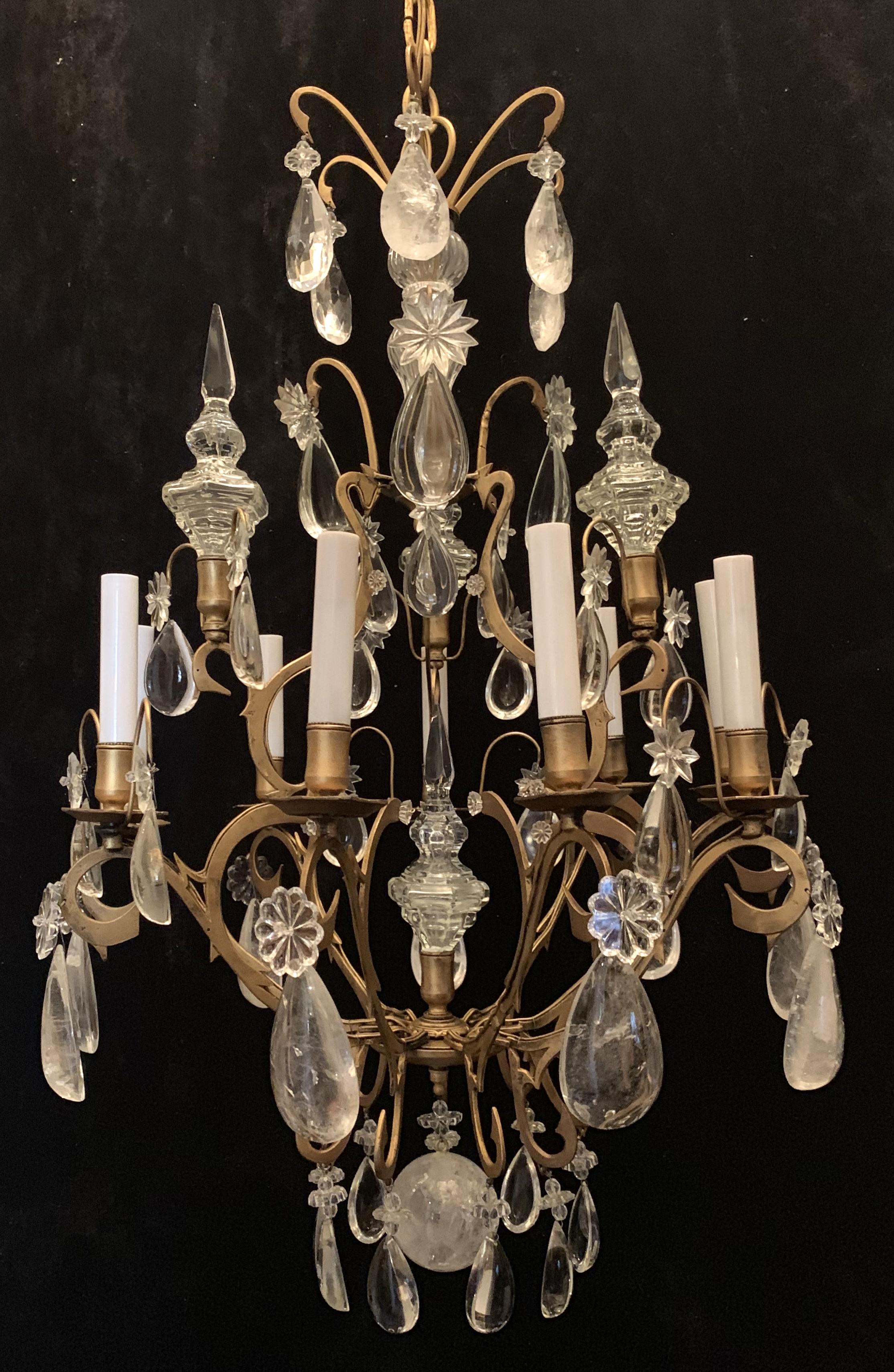 Wonderful soft scrolls accent the body of this nine light Baguès / Jansen style rock crystal chandelier with centre and 3 surrounding finials and lovely layers of clear crystal prisms accented by the rock crystal.
Completely rewired and comes with