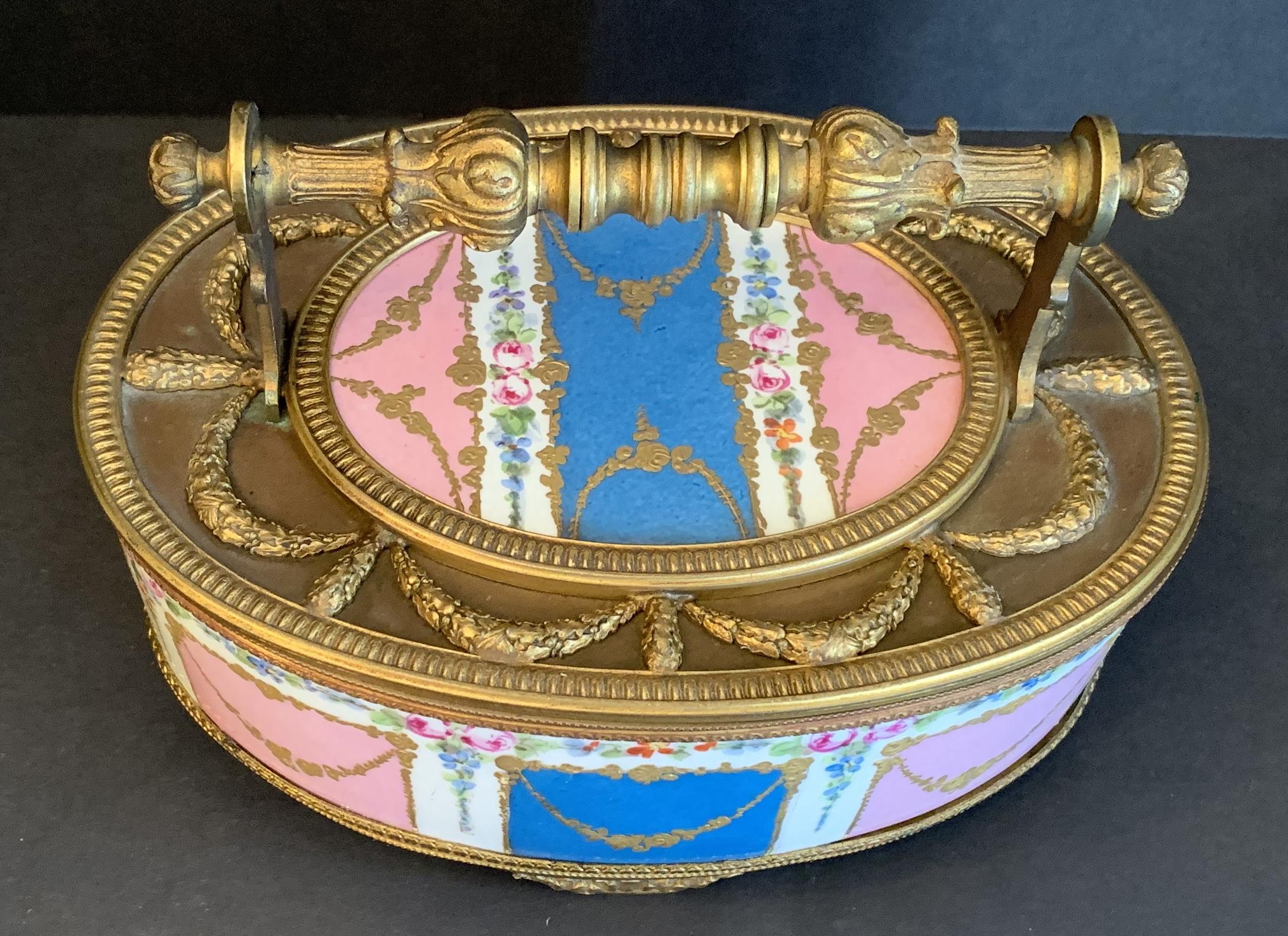 A wonderful French hand painted swag Sèvres Porcelain and bronze ormolu mounted oval casket box with removable lid raised on bronze acanthus leaf feet.