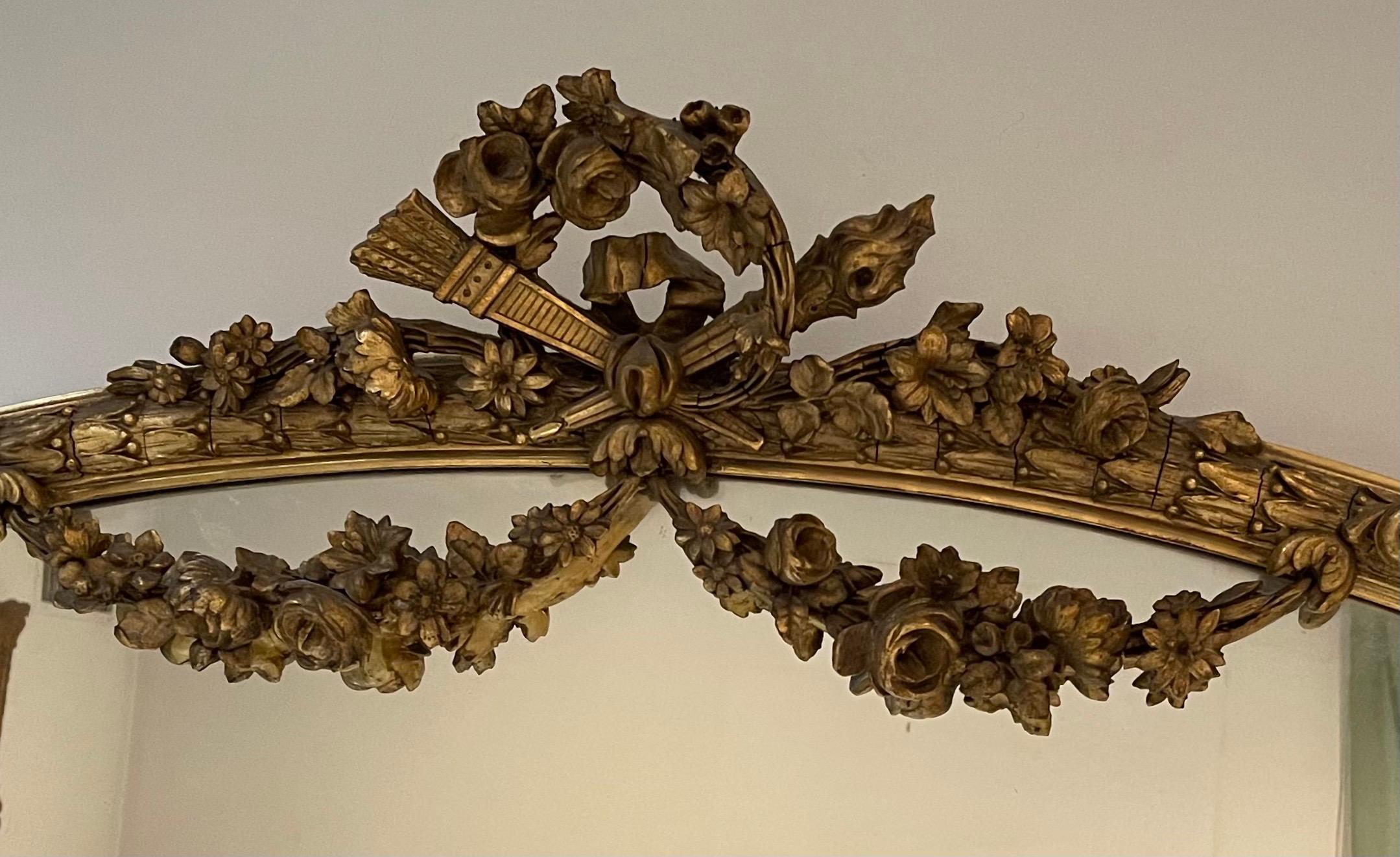 A wonderful French Louis XVI style horizontal oval giltwood with floral swags draping over the mirror, and a beautiful center crest of two cross torches. Very fine chasing and detail.
Measures: 51
