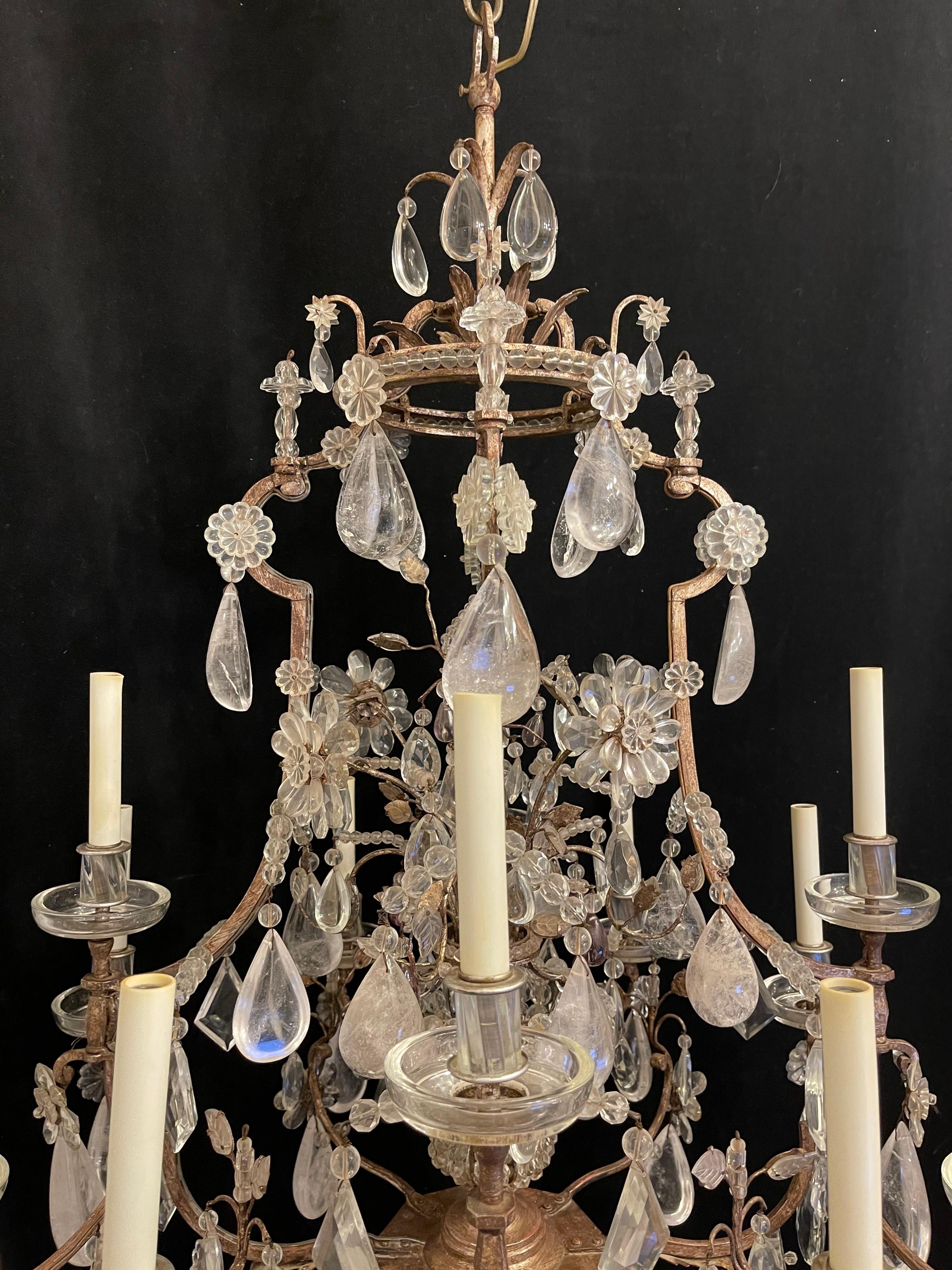 This large scale, stylish and chic rock crystal chandelier was created by the iconic firm of Maison Baguès and is in the Louis XV style with its 12 candle lights and the interior crystal beaded cage has a single bulb. The steel frame is an antique