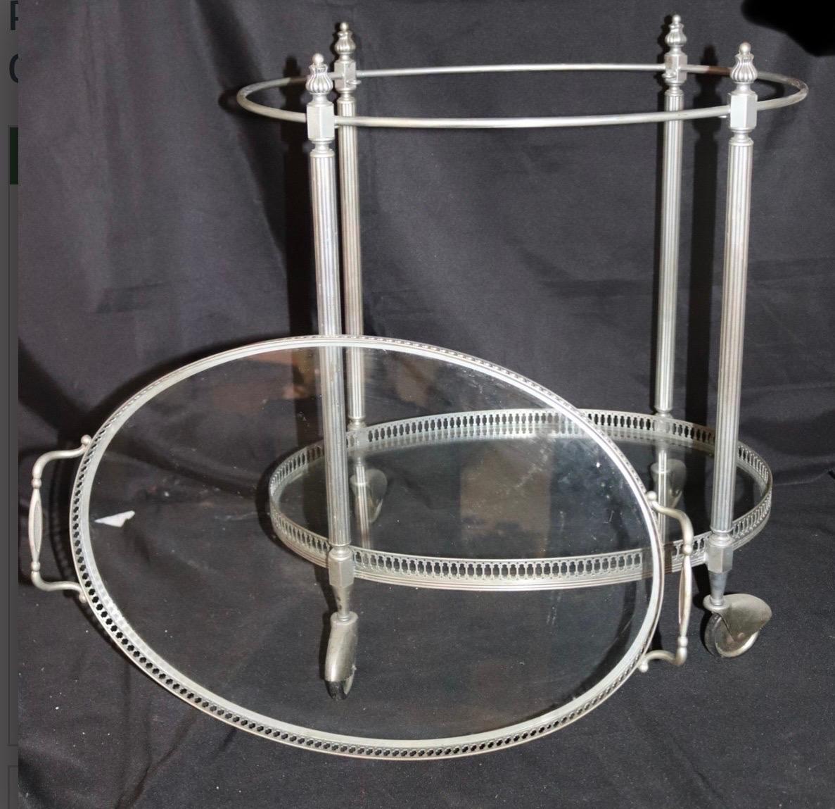 A wonderful French neoclassic style 2 tier nickel plated oval bar cart with inset glass shelves and removal gallery tray top. The nickel plating is in good overall condition. High quality workmanship throughout including refined delicate gallery