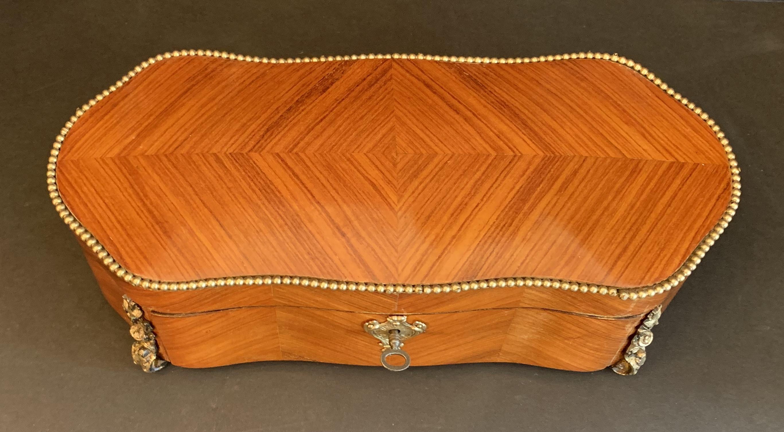 An unusual French ormolu bronze mounted book matched fruitwood marquetry drop front casket with original working key.