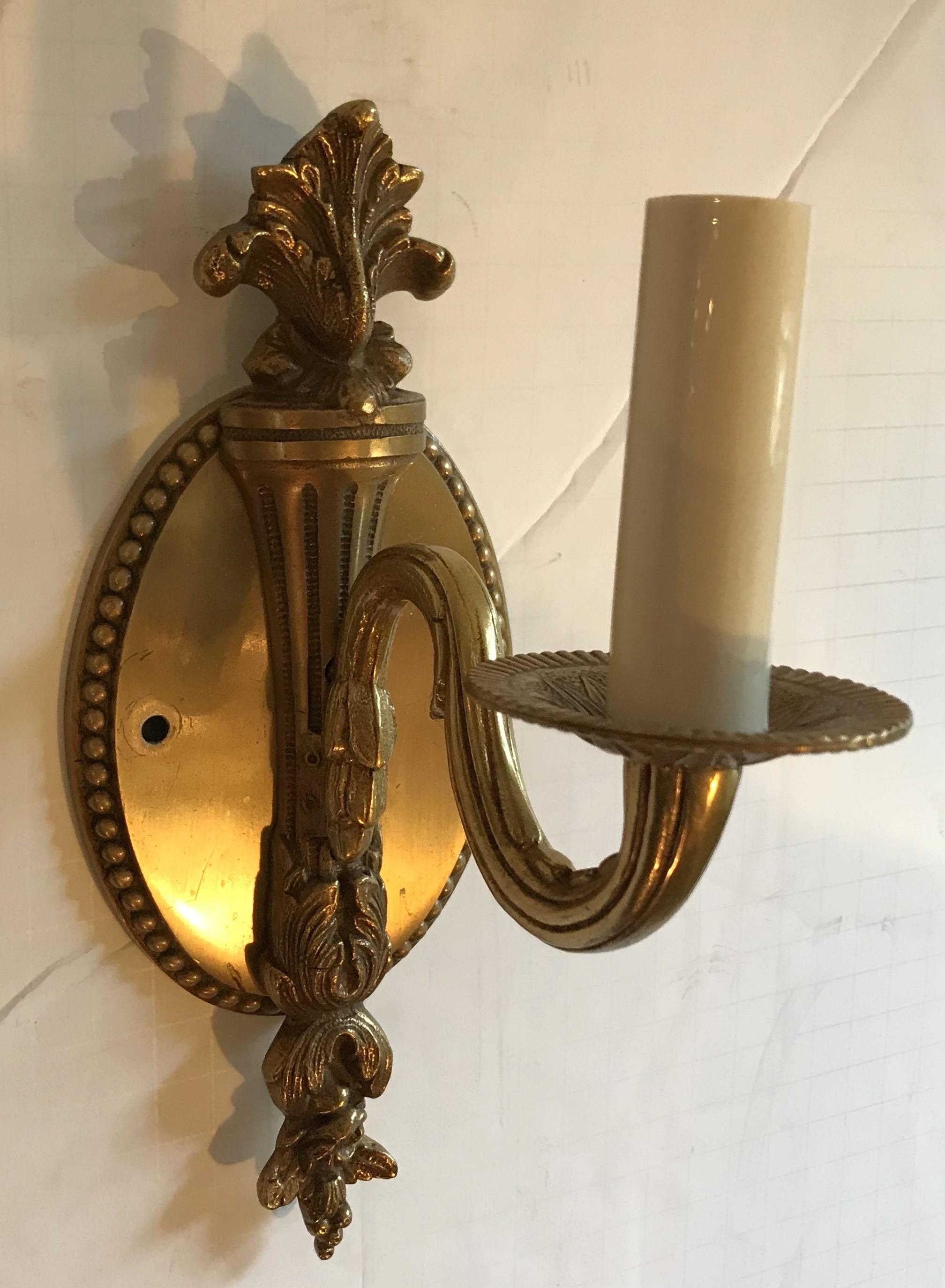 Une merveilleuse torchère néoclassique simple de style français, en bronze patiné ancien, avec une plaque arrière ovale et filigrane. Câblage certifié UL et prêt à être installé. A la manière de Caldwell.
Détails.