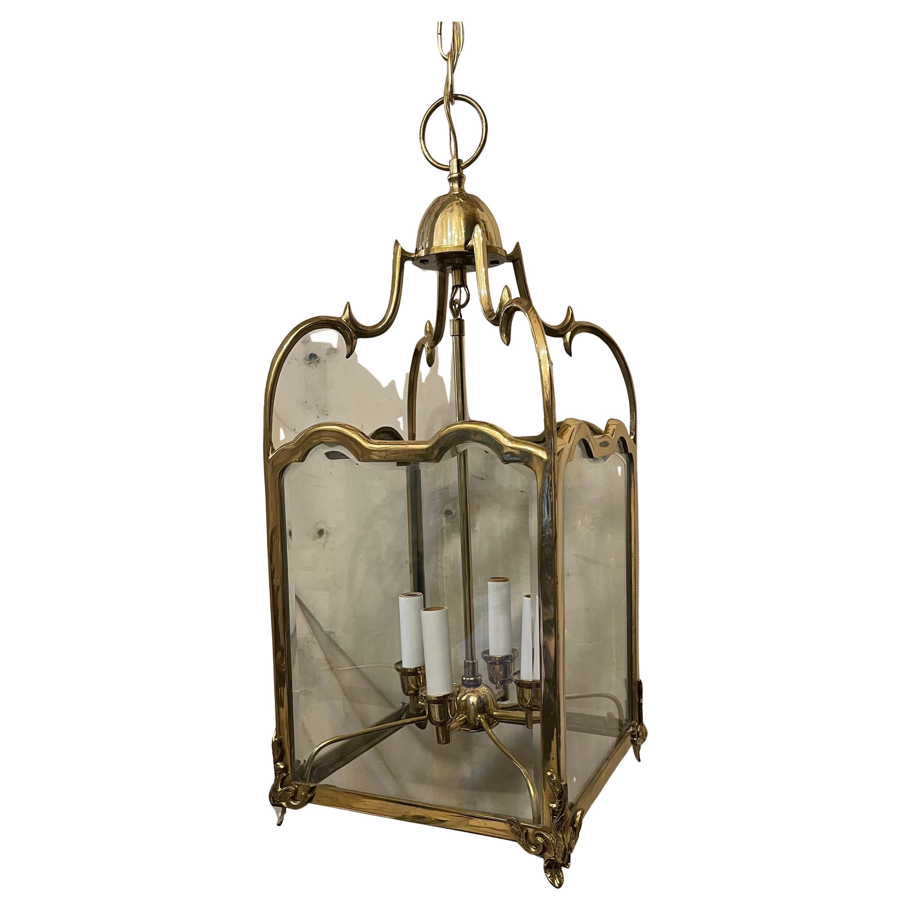 Merveilleuse lanterne suspendue en laiton poli de style Louis XV, de forme carrée avec panneau de verre biseauté, dotée d'une grappe de 4 lampes candélabres.
Livré prêt à être installé avec un auvent en chaîne et la quincaillerie de montage
Dans la