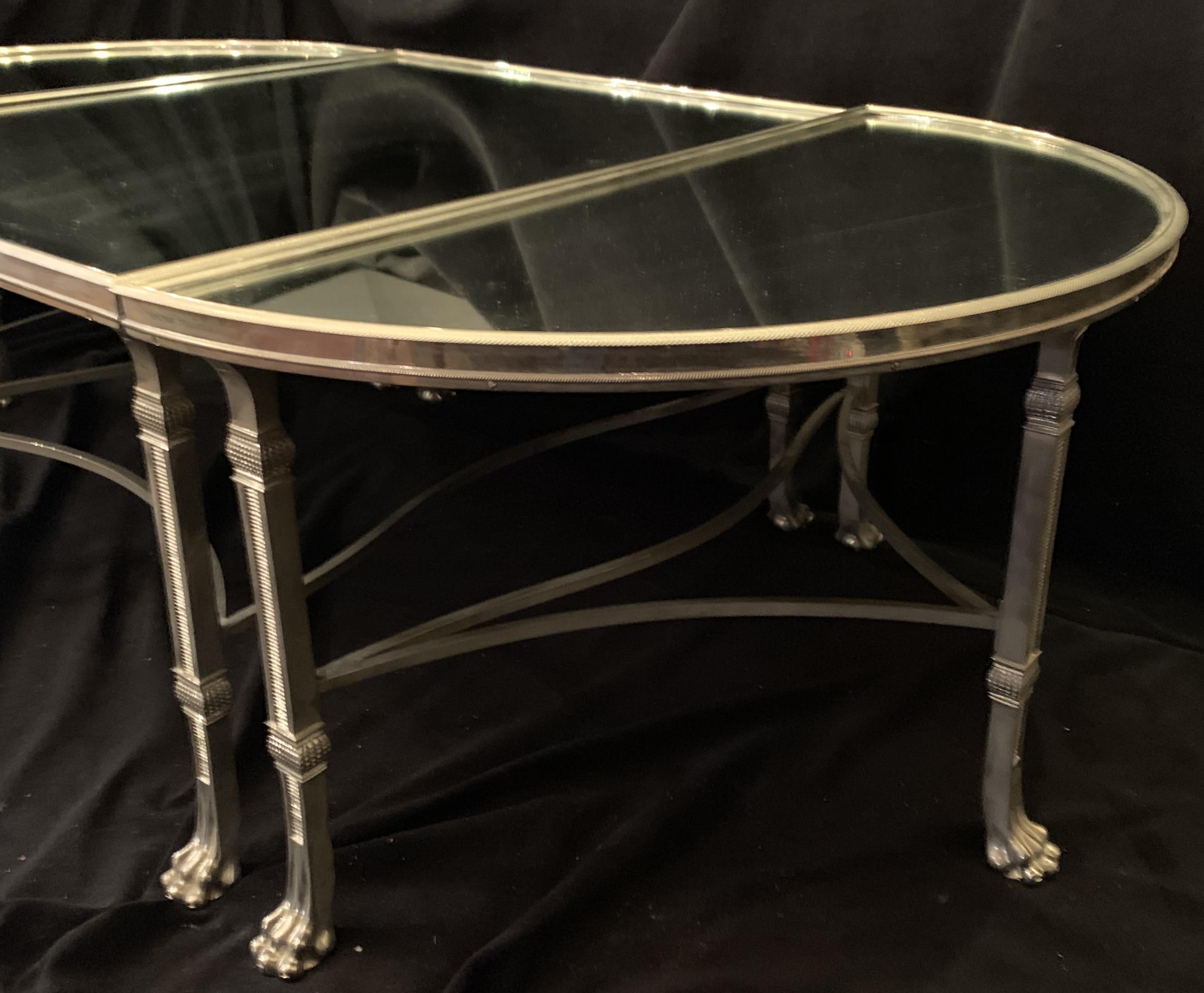 A Wonderful French silver polished nickel over bronze and mirrored three part cocktail / coffee table in the Regency style, with paw feet and stretchers across the bottom. Consisting of a square center sections and two rounded ends that are