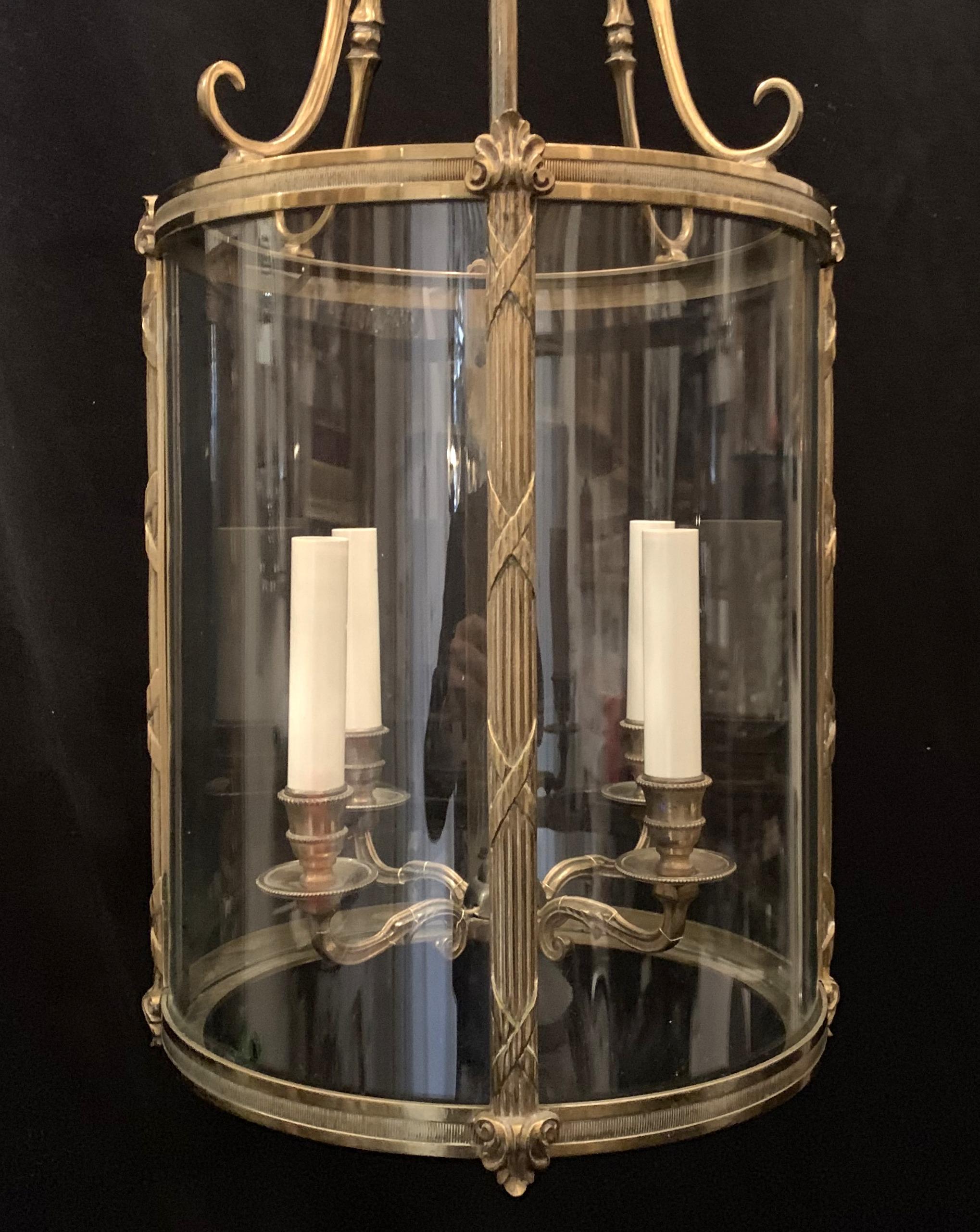 Perfect for a hallway or a covered porch, this Classic gilt bronze and curved glass four light lantern. With beautiful scrolls curving at the top and supporting the lights, and beautiful etching around the bronze edges and supports of the glass,