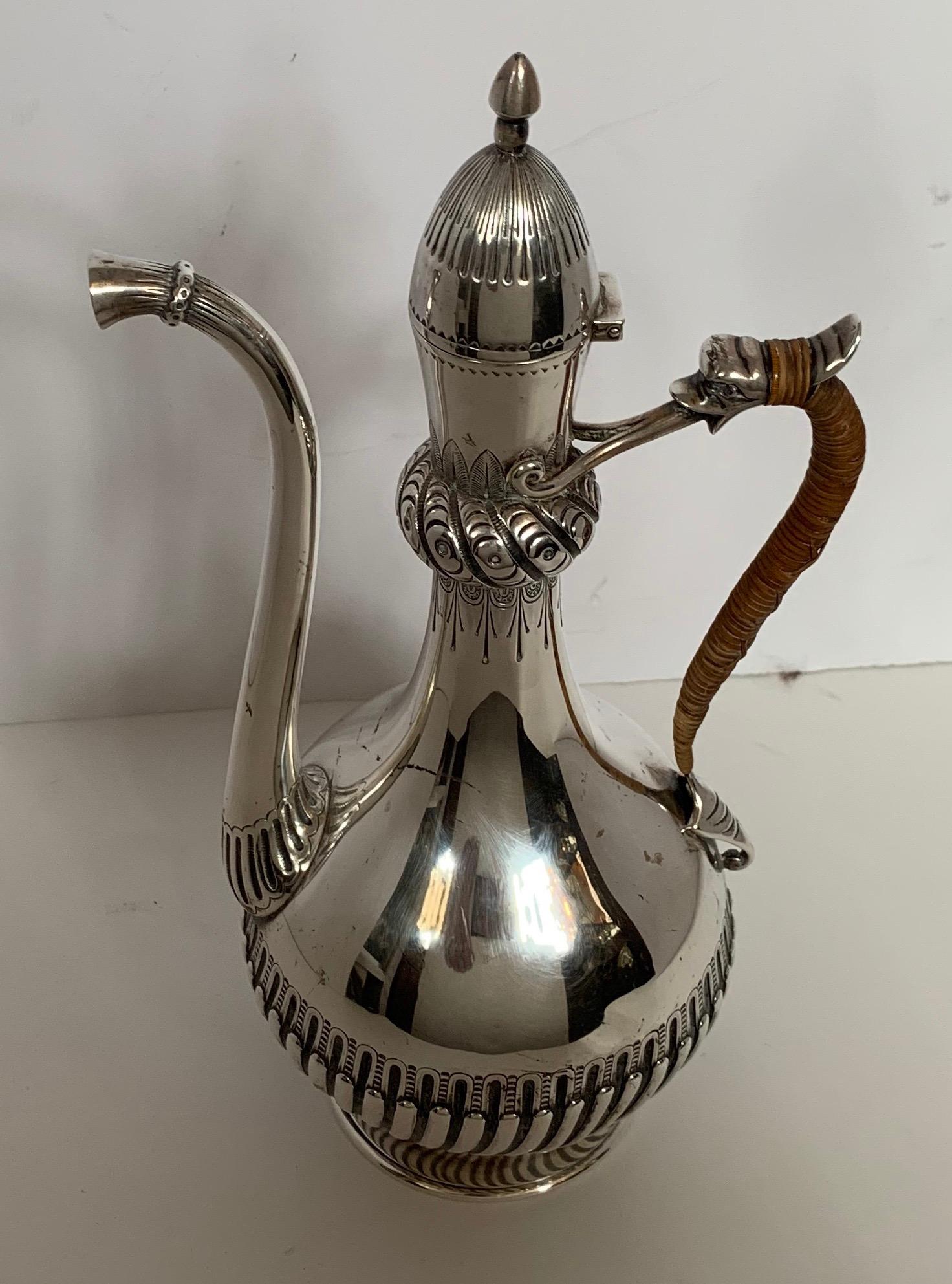 A wonderful North American sterling silver black coffee pot, Gorham Mfg. Co., Providence, Ri, Baluster form with long slender spout, the lower body embossed, the handle wrapped with rattan & topped by a dolphin head, with a hinged dome