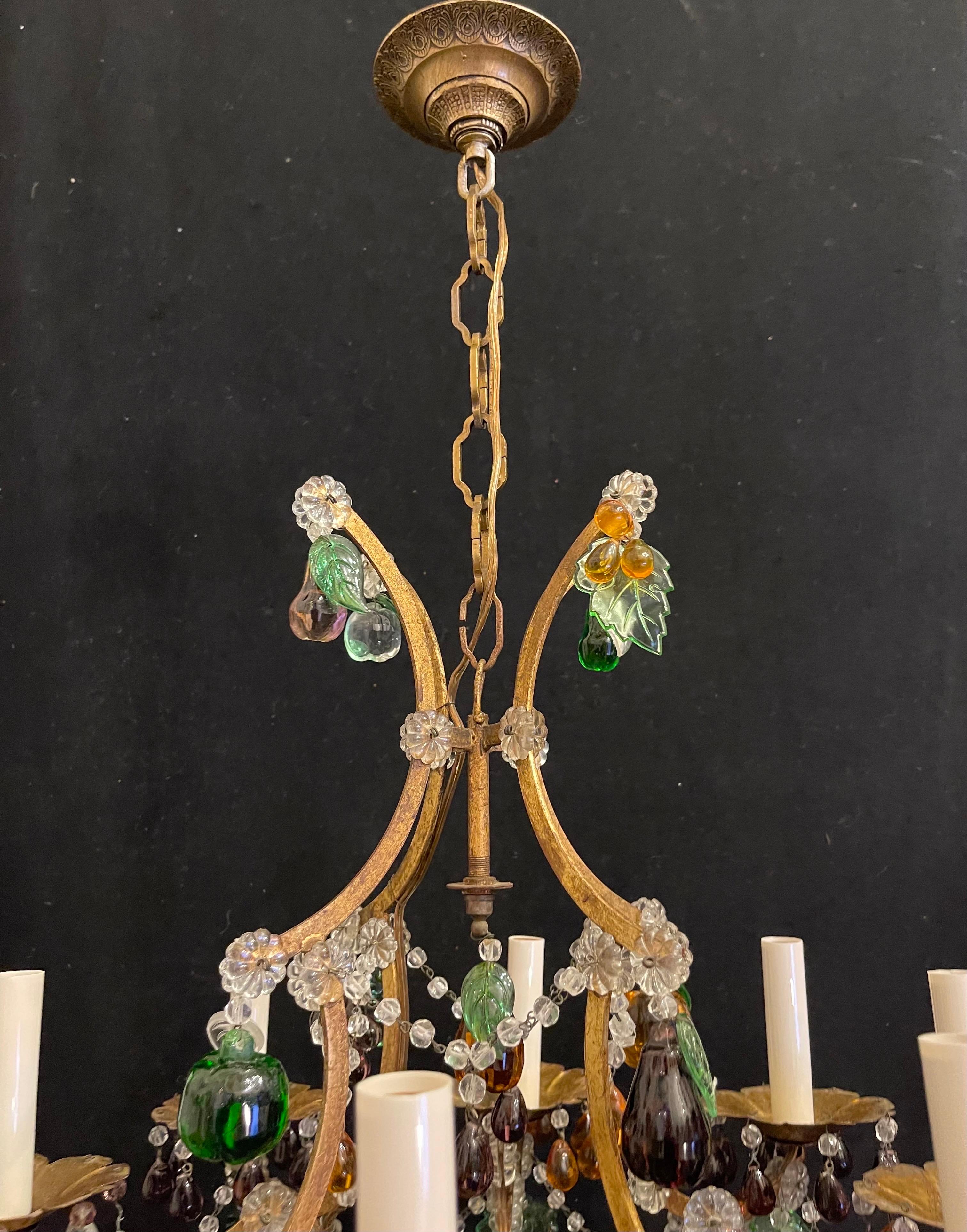 Magnifique fruit d'art italien des années 1950 en fer doré et cristal de Murano.  lustre décoré à 8 candélabres.
Ce magnifique lustre se compose d'une cage à oiseaux en fer doré gracieusement chantournée et d'un assortiment de fruits en verre coloré