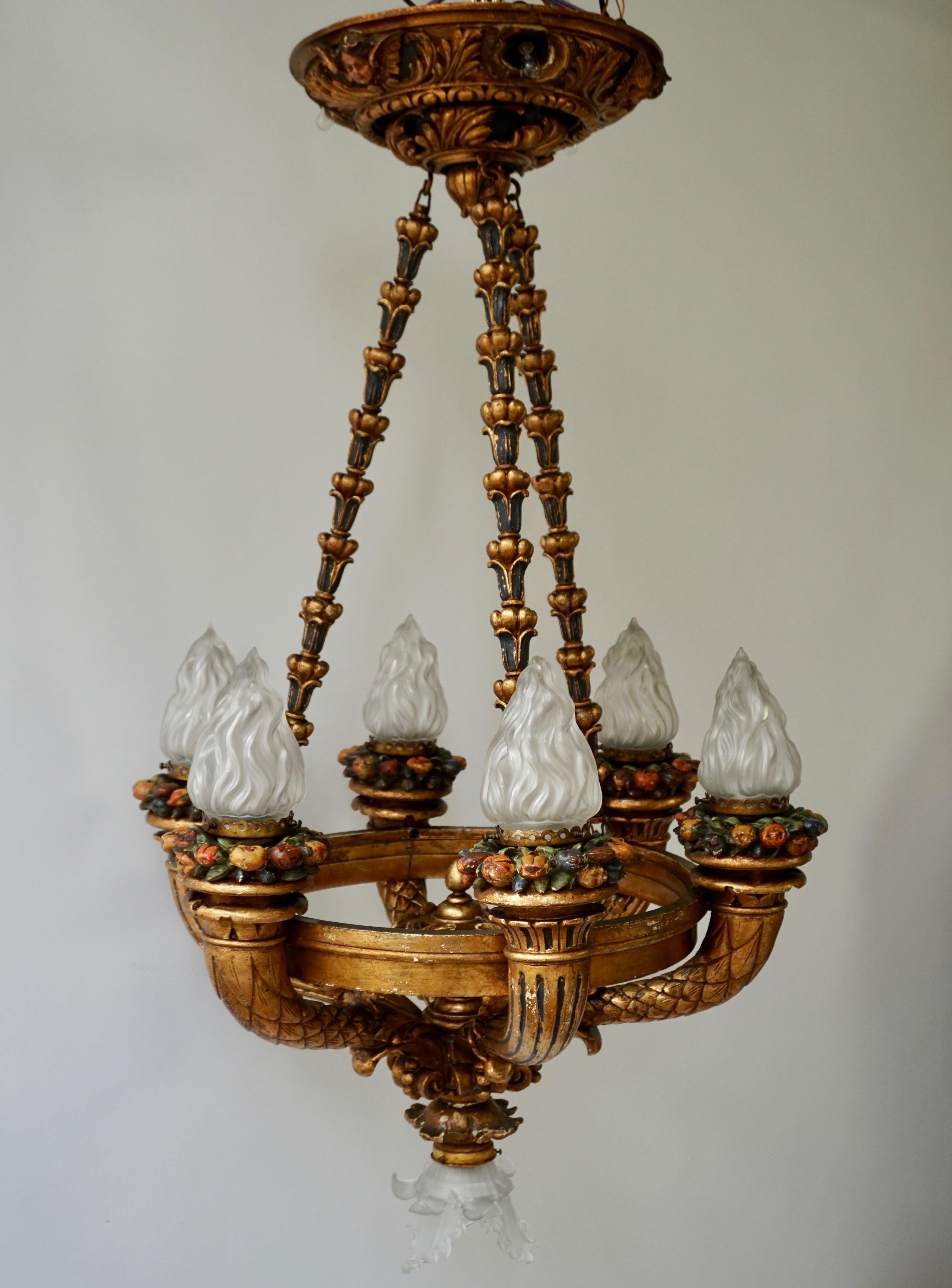 Unique Italian gilt wooden chandelier with seven lights, cherubs and painted fruit. Fine gilded wooden leaves and six beautiful angels make this rococo chandelier unique. The round giltwood ceiling plate is decorated with three painted cherubs and