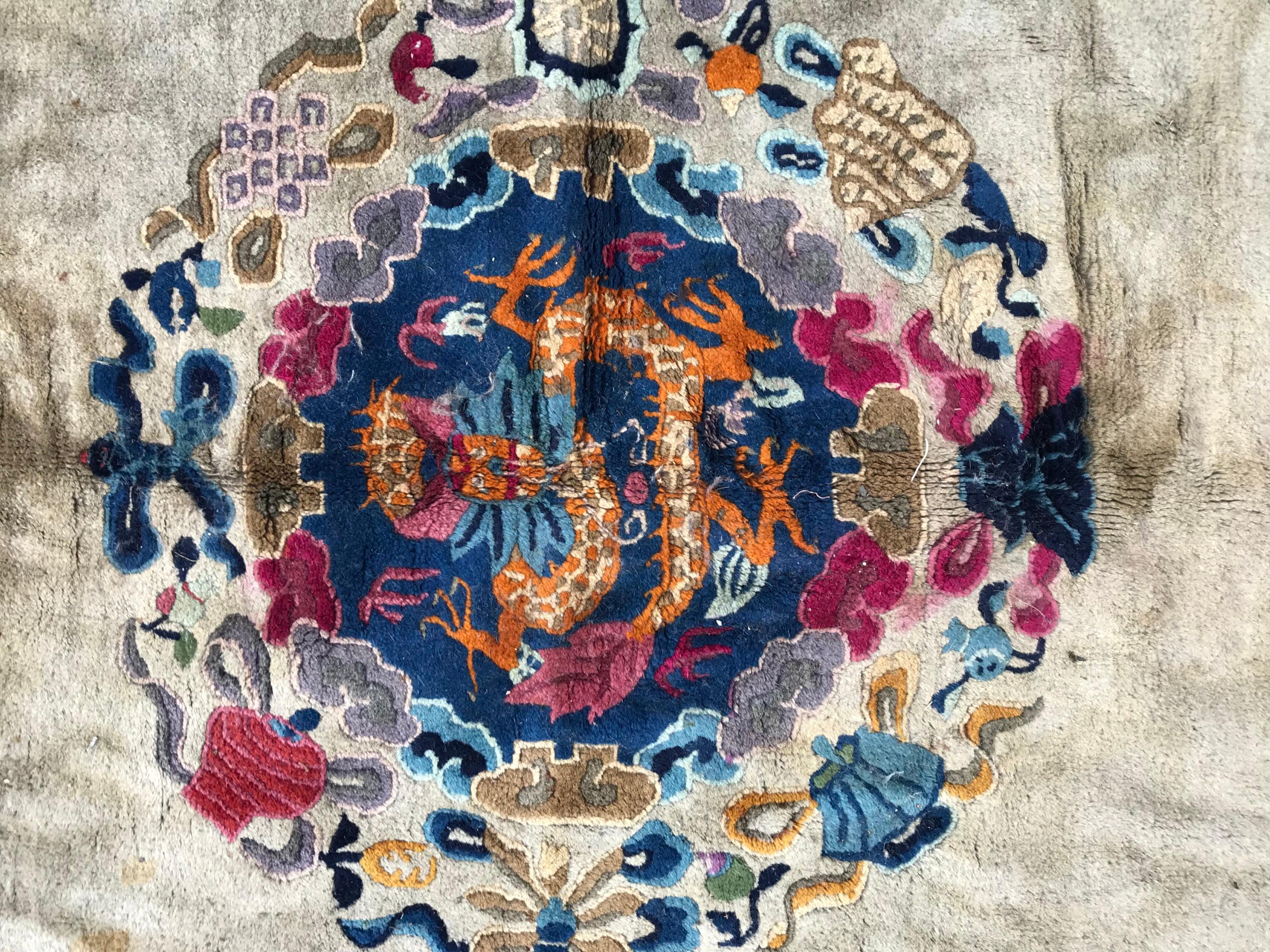Very beautiful early 20th century large Chinese rug with beautiful design with central dragon and four dogs around, beige color field, with blue and purple. Entirely hand knotted with wool velvet on cotton foundation.