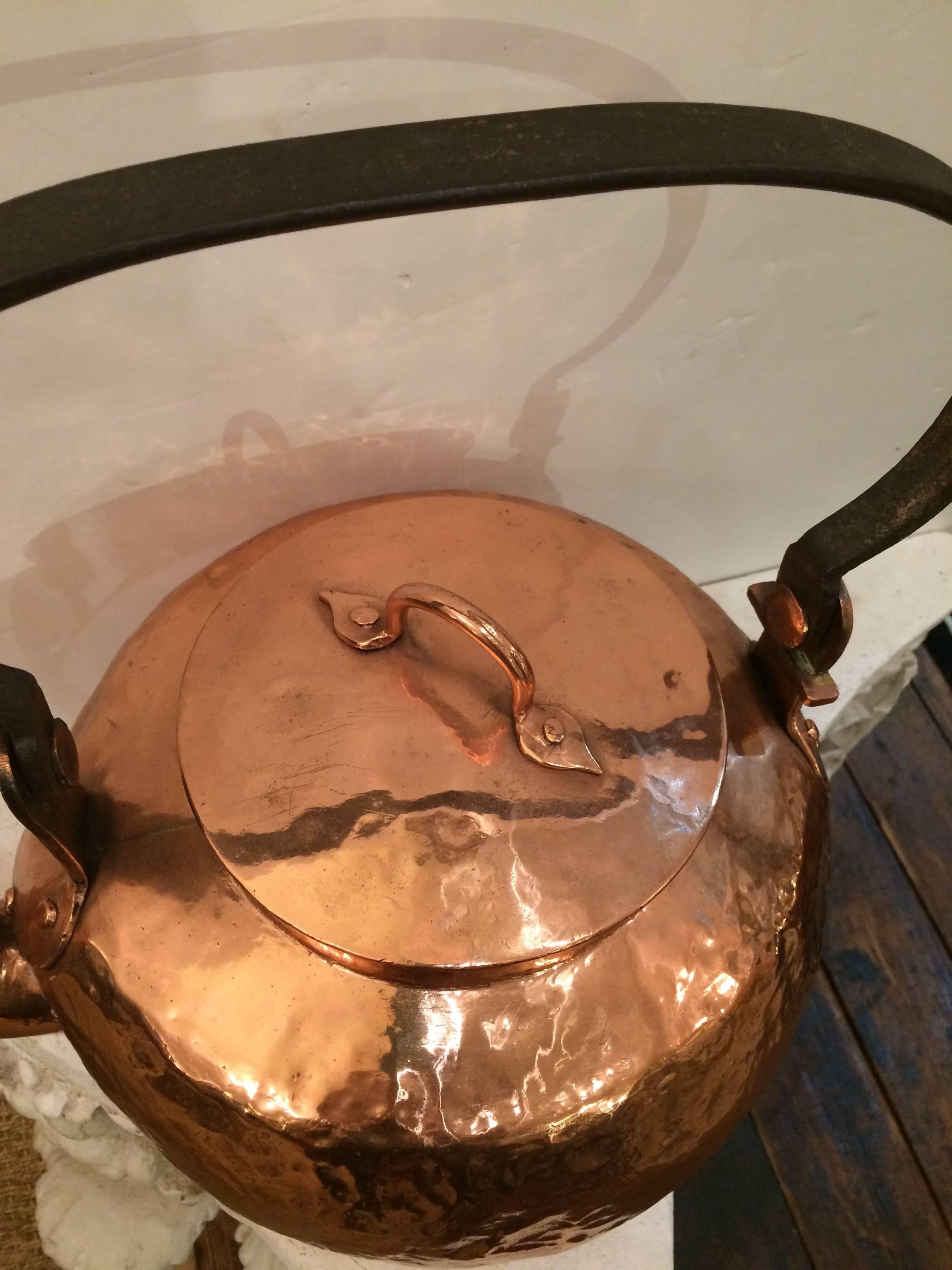 A very large beautiful shiny copper tea kettle with black iron handle. Measure: 12 inches H to top of lid.