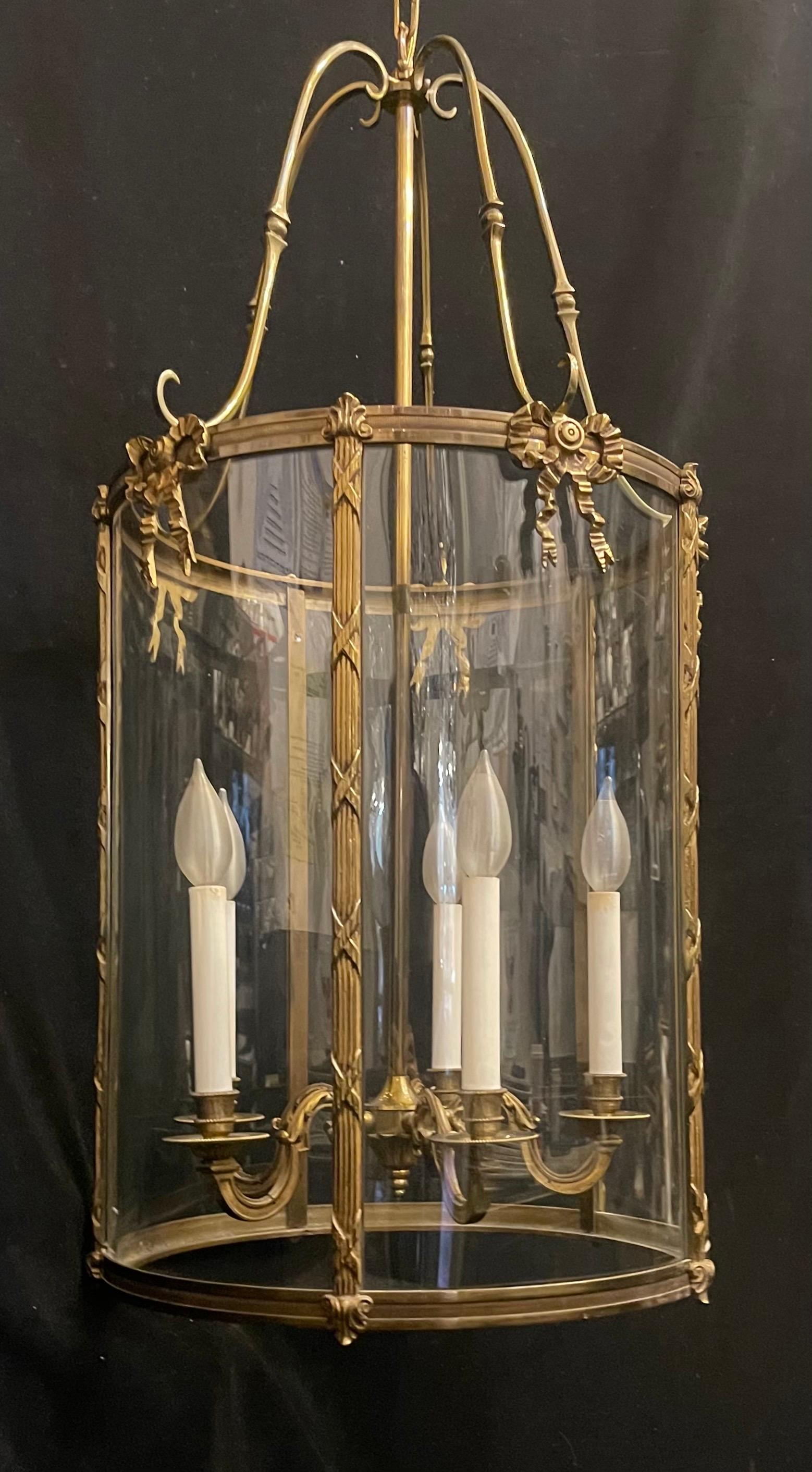 Cette élégante lanterne à cinq lumières en bronze doré est ornée d'une garniture en bronze strié et gravé. Le haut et le bas de la lanterne sont ornés d'une garniture en roseau cannelé avec des arcs en croix autour d'un panneau de verre incurvé