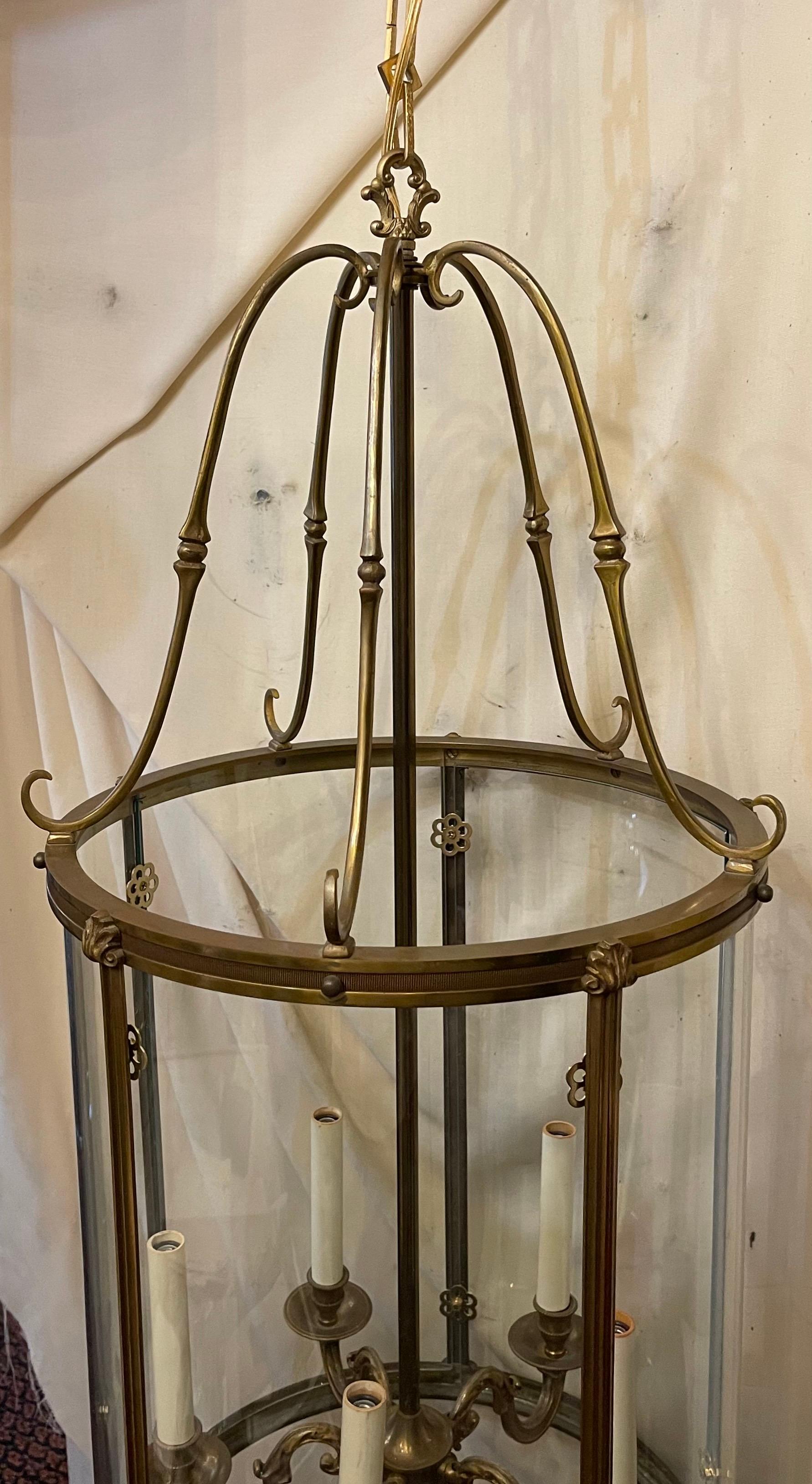 Eine elegante, fünfflammige Doré-Bronze-Laterne mit geätzter, gerippter Bronzeverzierung an der Ober- und Unterseite der Laterne und geriffeltem Schilfrohr um eine geschwungene Glasscheibe herum; die Leuchte hat fünf Arme mit schönen Schnörkeln, die