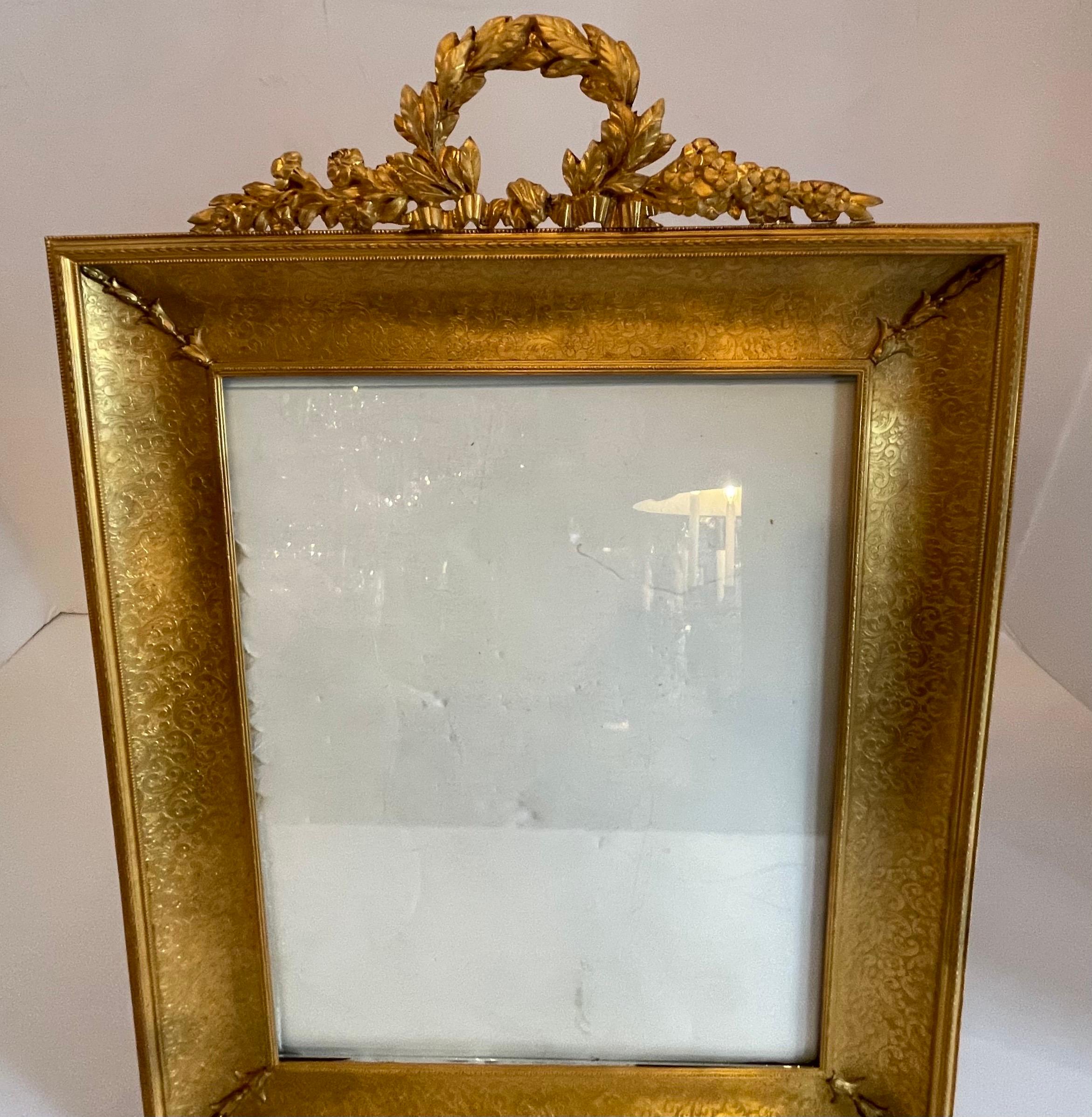 A wonderful large French Louis XVI style, dore bronze picture frame with bow wreath garland crown.