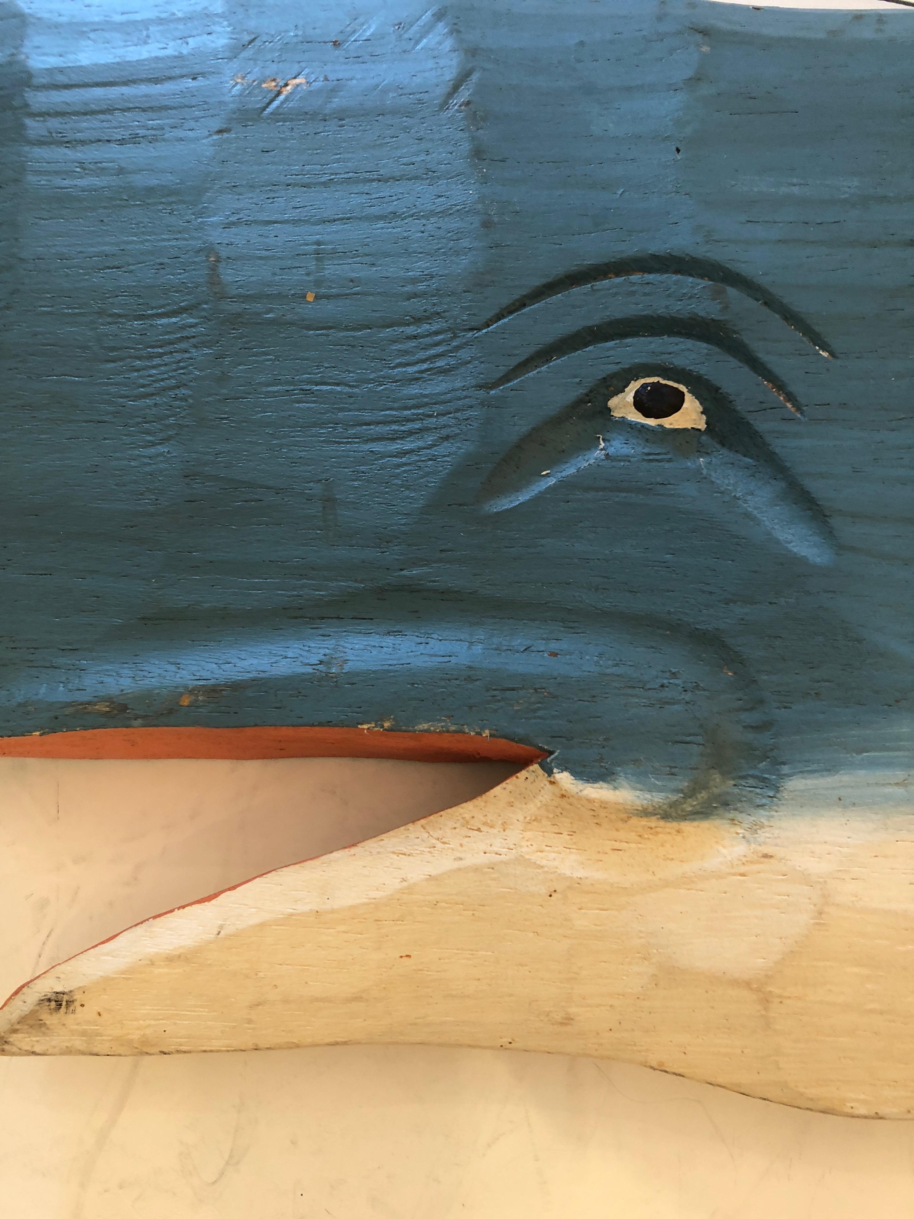 A large whimsical wall sculpture of a blue whale finished on both sides and having a fabulously expressive eye.