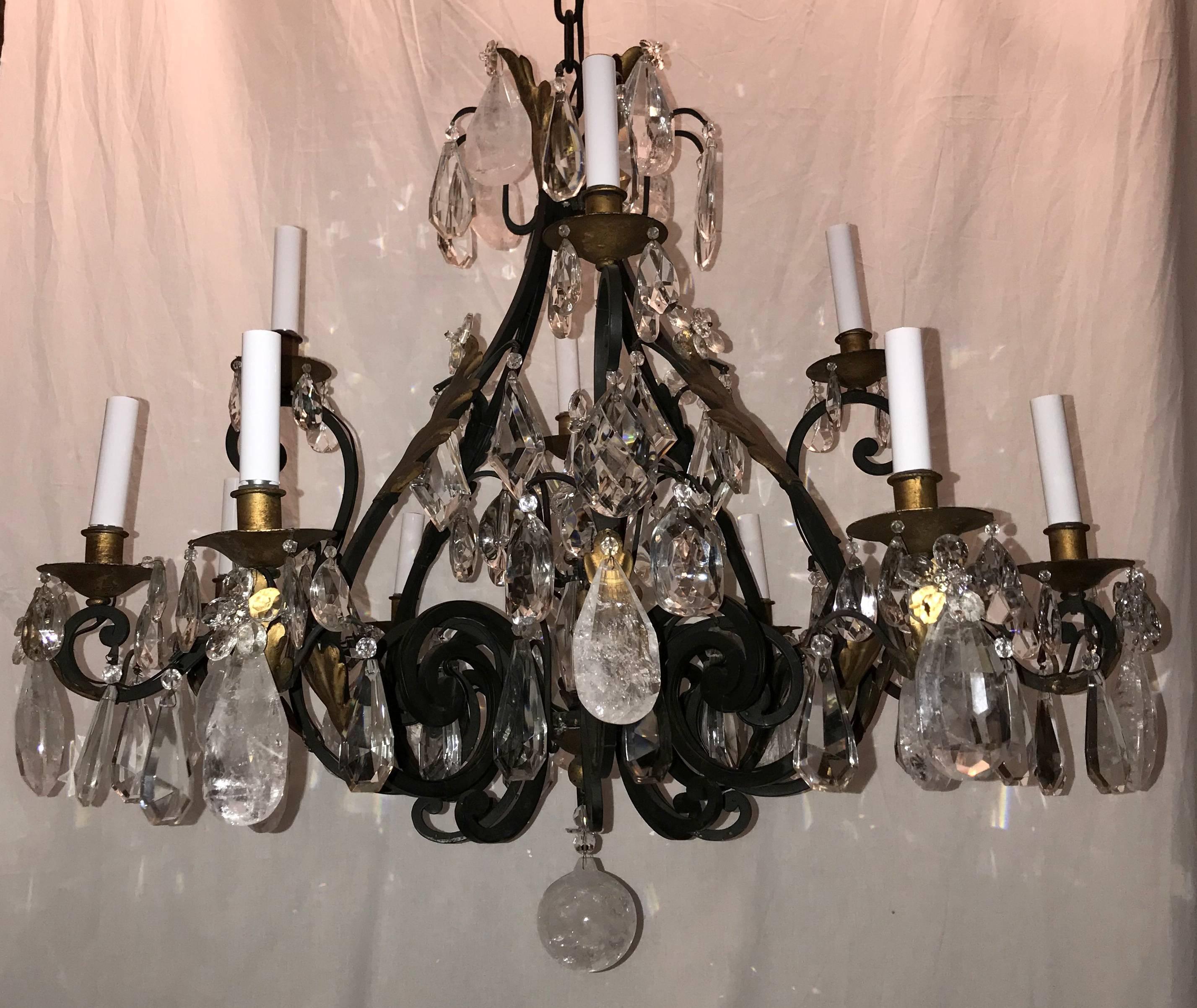 A wonderful large Maison Baguès style Louis XV French iron and gilt rock crystal and alternating faceted crystal chandelier adorned with flower crystals throughout and finished in the center with a beautiful crystal obelisk spike. Consisting of 12